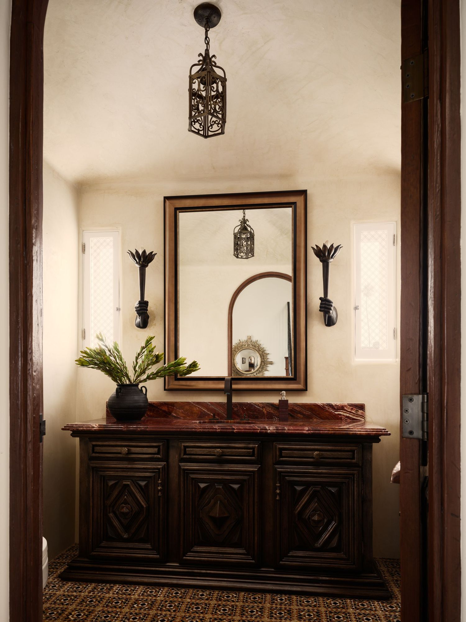 Bathroom vanity at 7757 Whitefield with carved wood cabinetry, stone countertop, iron lantern pendant, and vintage tile flooring.