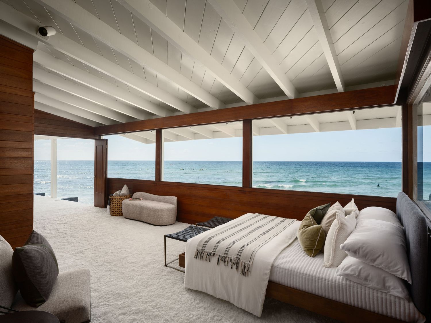 Primary bedroom at 1890 Spindrift Drive with expansive ocean-facing windows, exposed beam ceiling, and serene midcentury interiors.