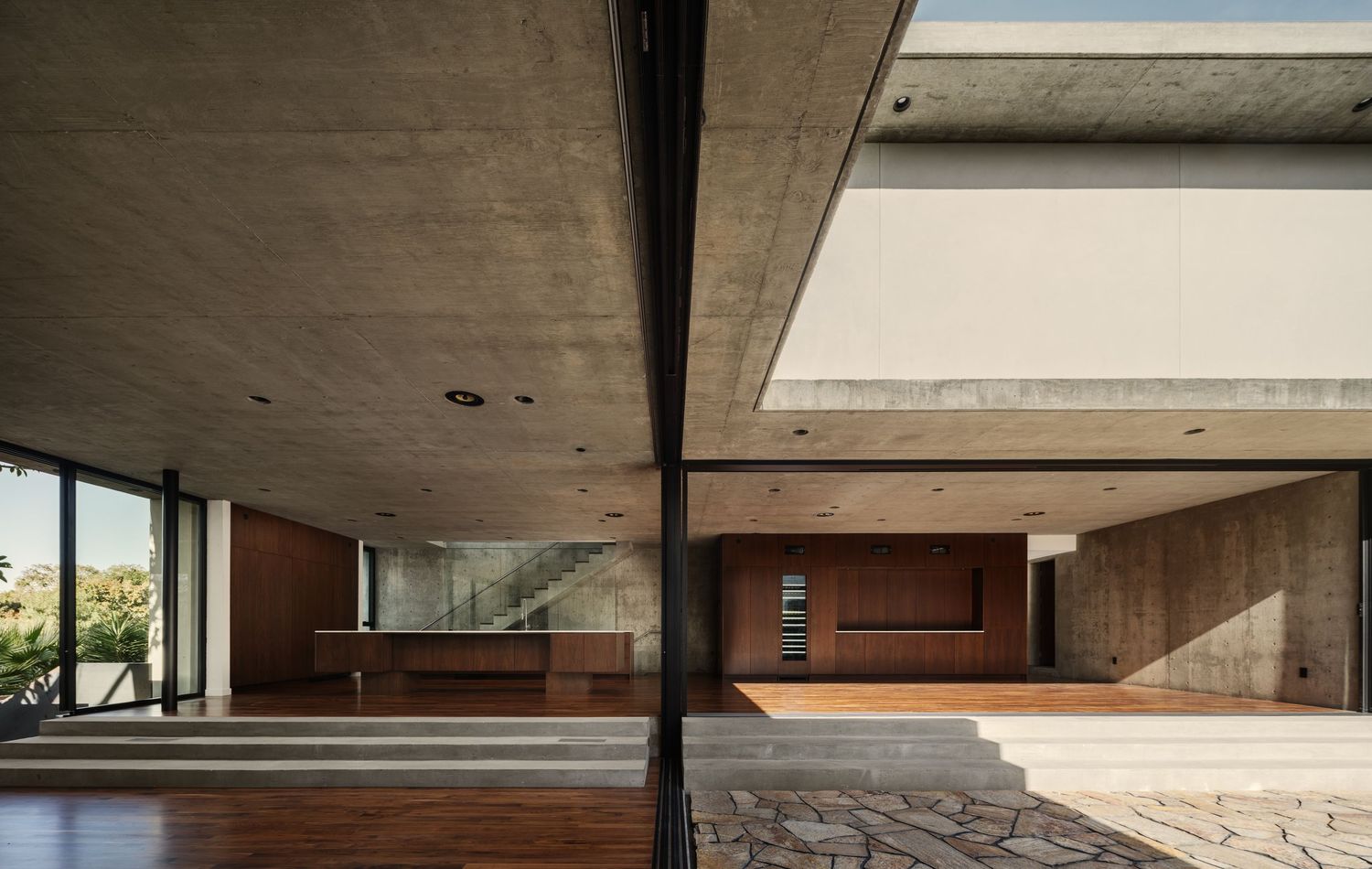 Arista Residence living area by Matthew Segal, concrete and wood interiors opening to courtyard—architectural photo by Luca Prodi.