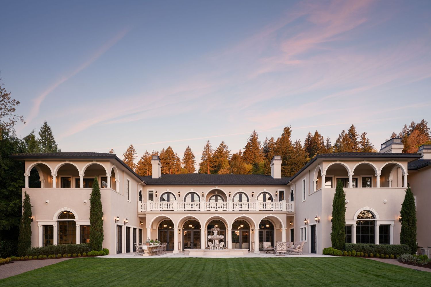 Architectural photo of the Fielding House estate captured at dusk, showcasing its Italianate arches, grand lawn, and symmetrical facade.