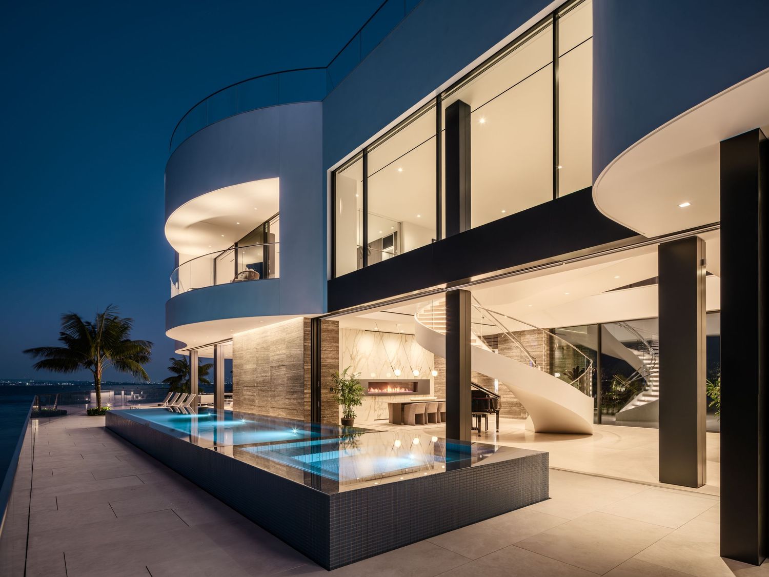 Night view of Coronado 3 The Point luxury waterfront residence featuring curved facade, pool, and illuminated interiors