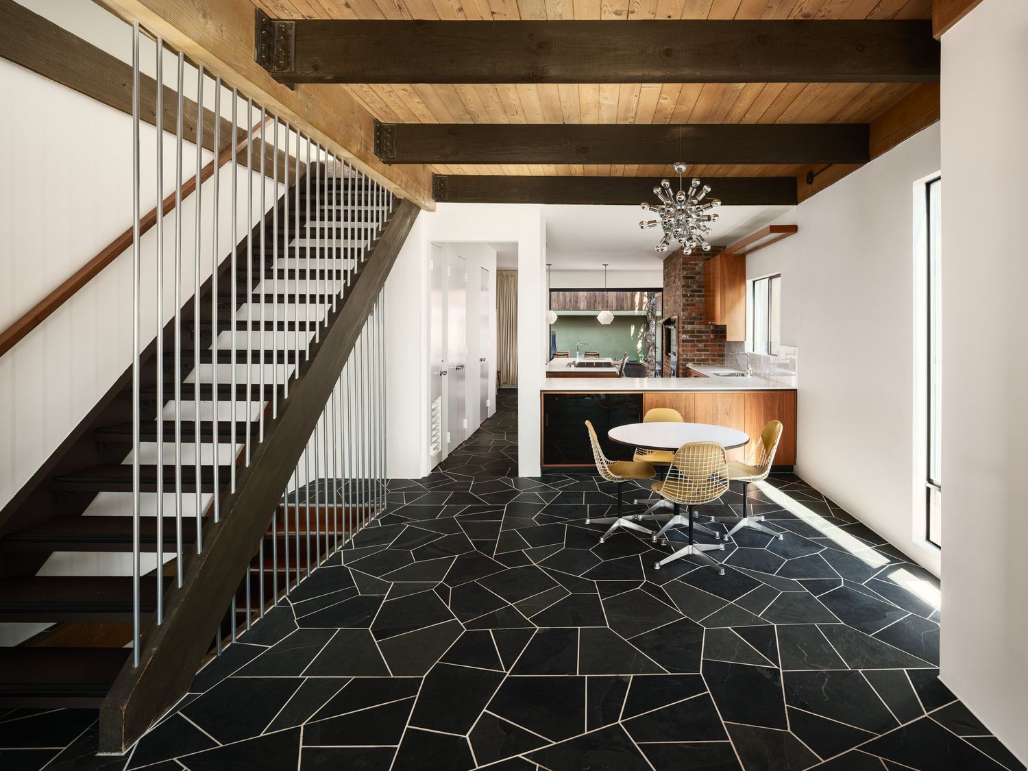 Open-plan stair hall with slate flooring, modern metal stair and dining area leading to the chef’s kitchen at the Liepman Residence