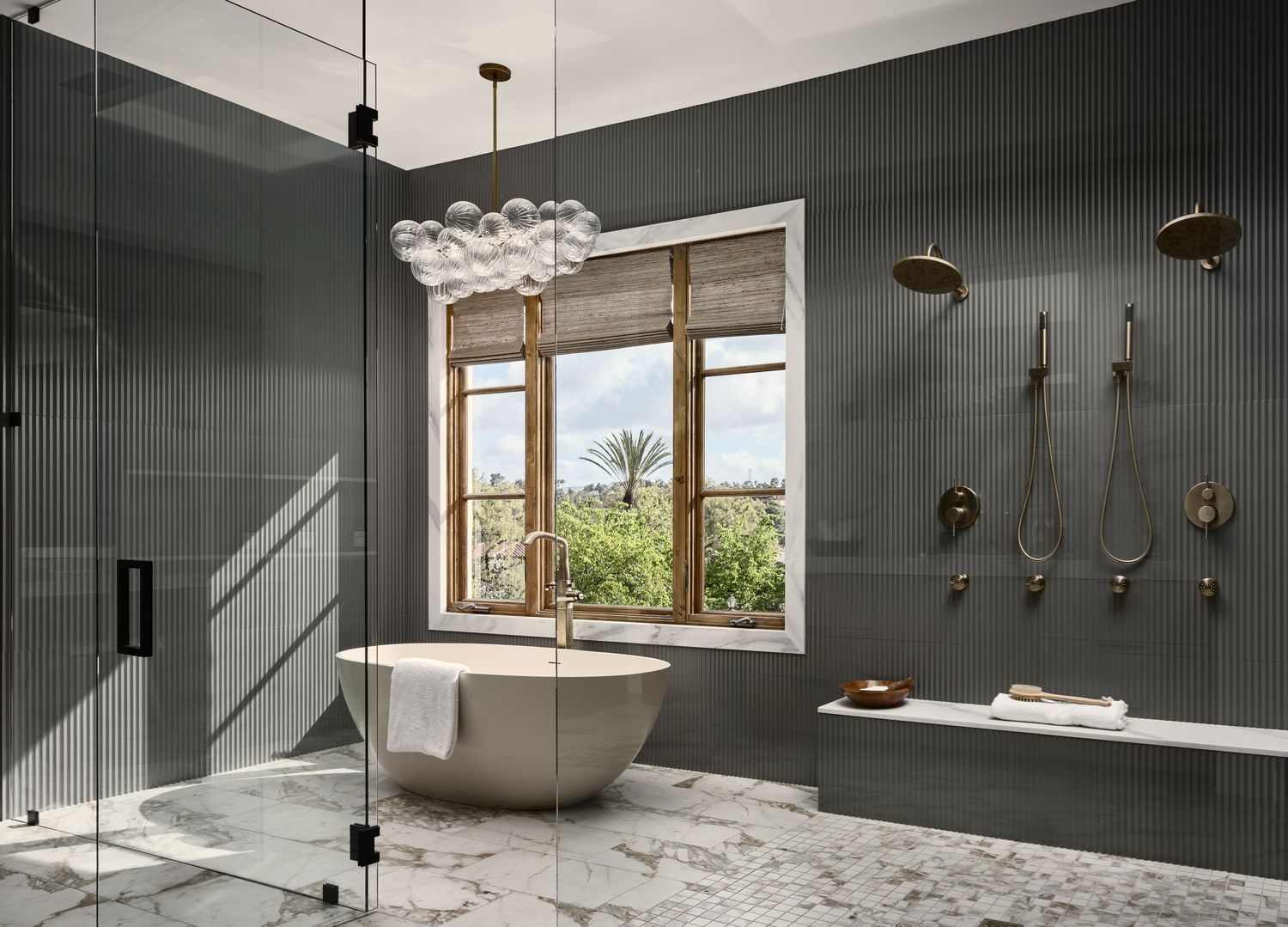 Luxury bathroom photographed in Rancho Santa Fe home flip, featuring marble floors, freestanding tub, and matte black fixtures.