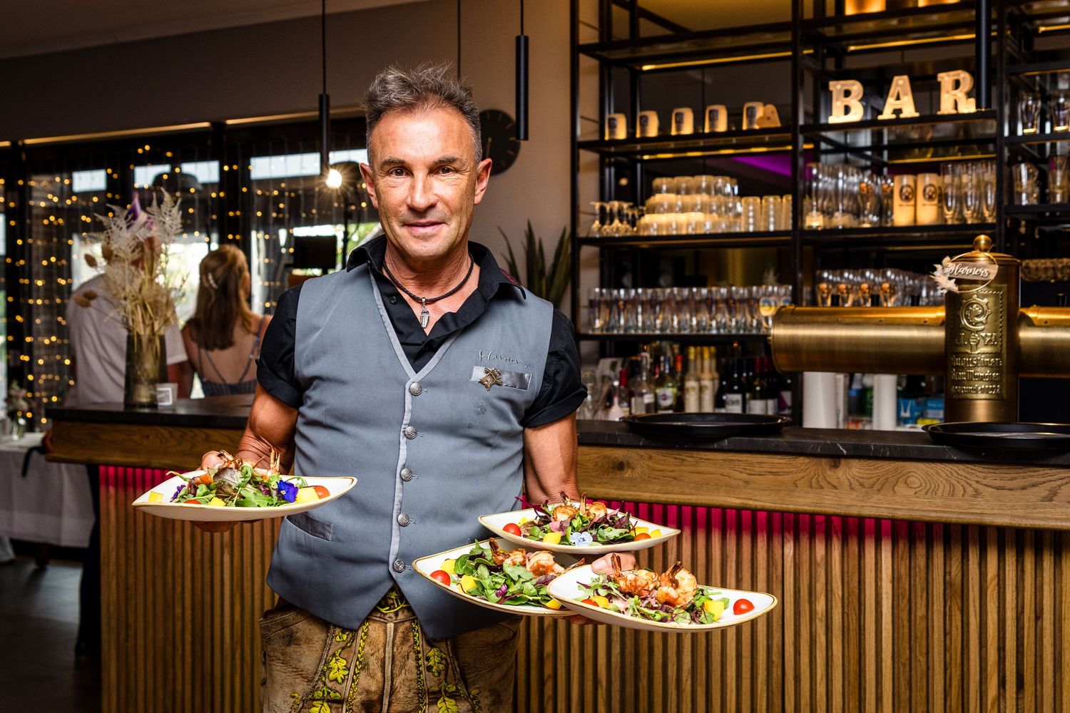 A person prepares fresh ingredients at a modern bar counter with bottles and glassware displayed in the background.