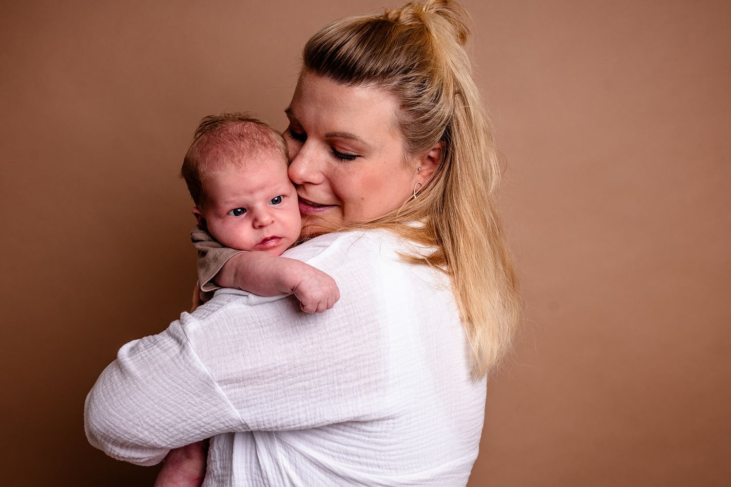 A tender moment between parent and newborn baby in soft brown tones captured in multiple connected photographs.