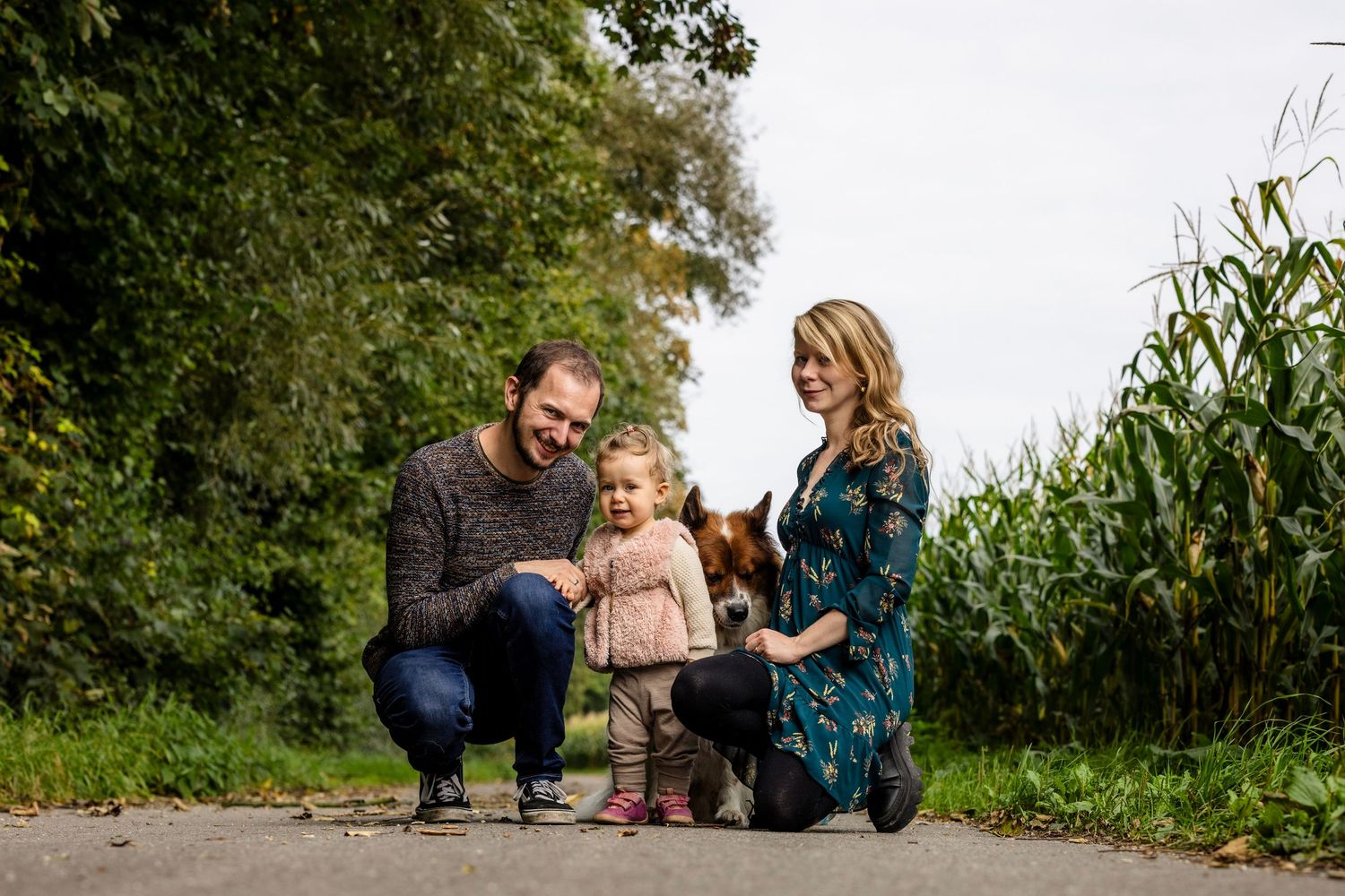 Family enjoying a peaceful moment together in a lush garden path surrounded by greenery and tall plants.