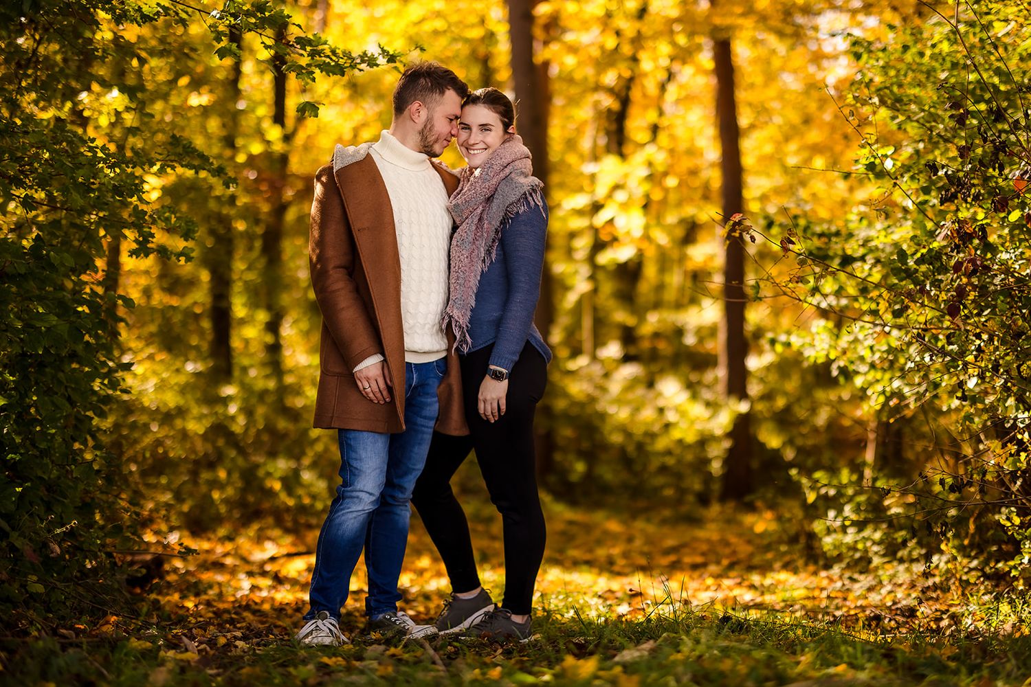 Autumn engagement photoshoot with golden foliage in background.