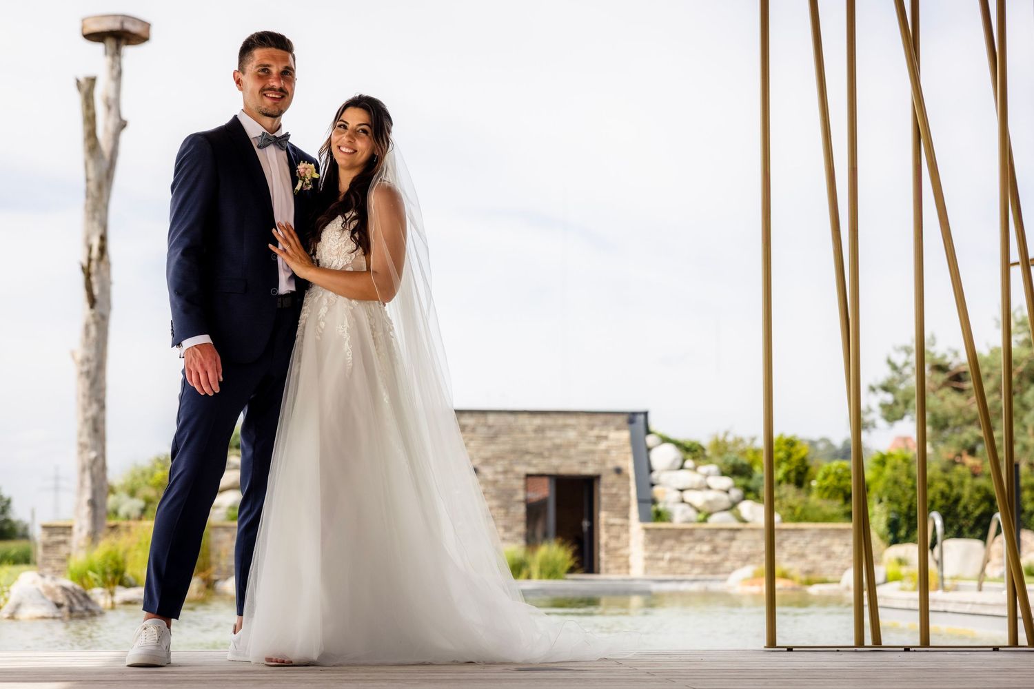 A couple shares a romantic moment on their wedding day against a backdrop of palm trees and waterfront views.