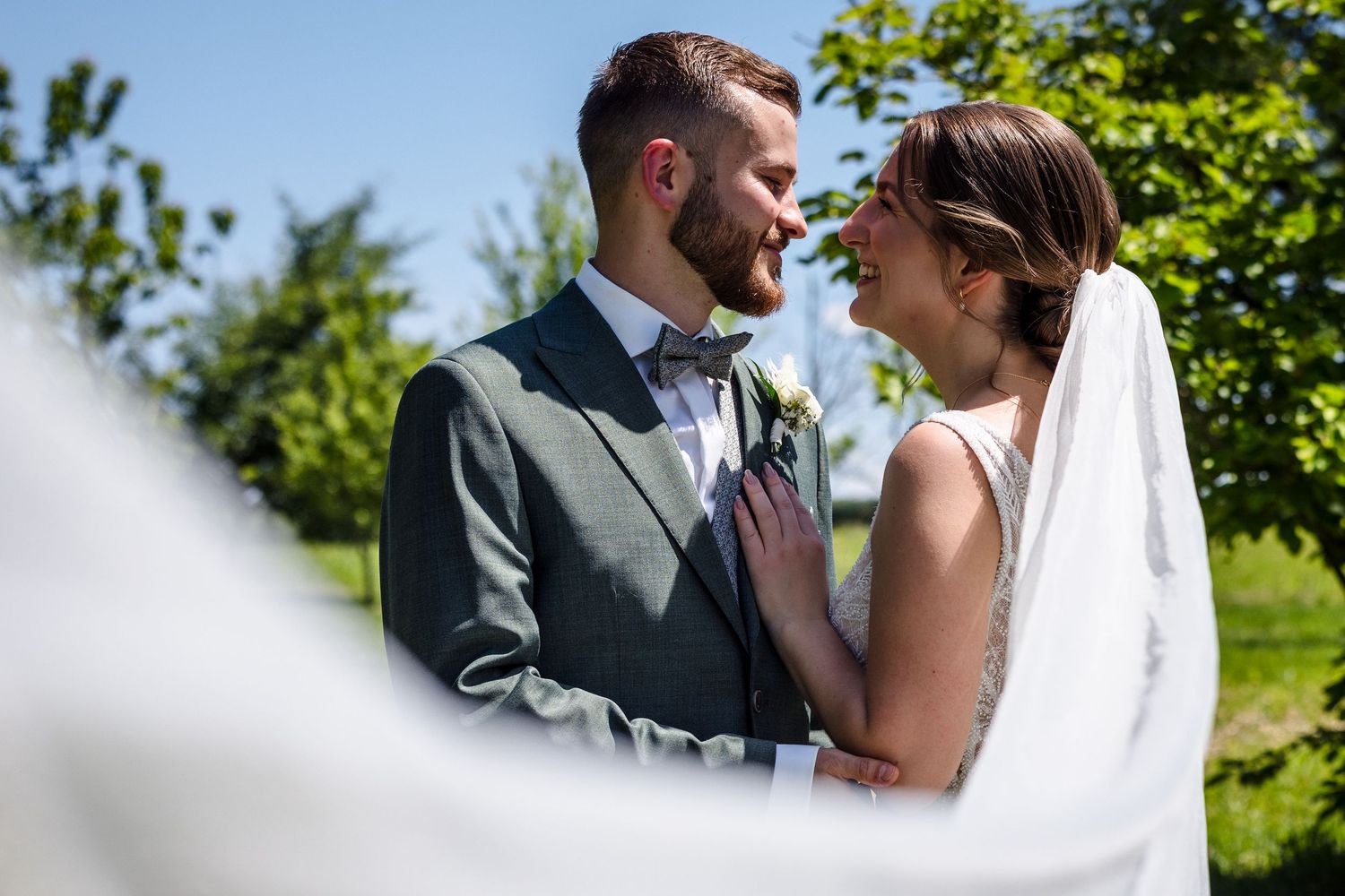 Hochzeitsfotograf Dachau Bride and groom share intimate moments in a sunny garden setting during their wedding photoshoot.