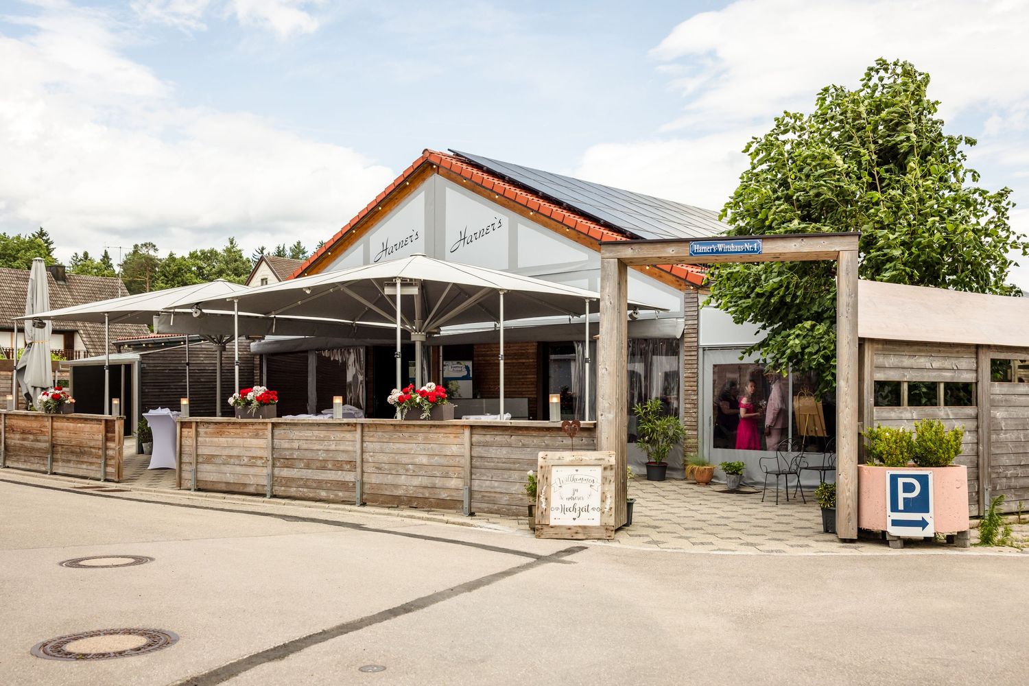Modern restaurant building with outdoor patio seating and orange-trimmed roof under blue sky.