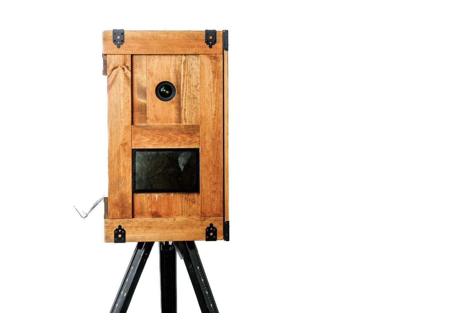 Antique wooden large format camera on a black tripod stand against a white background.