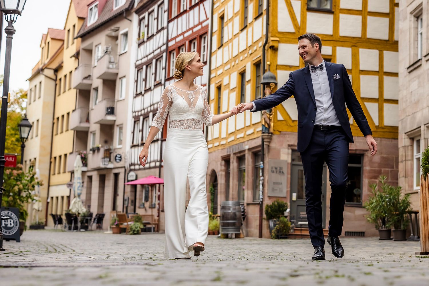 Cobblestone street with traditional German timber-frame buildings in warm yellow and white colors.