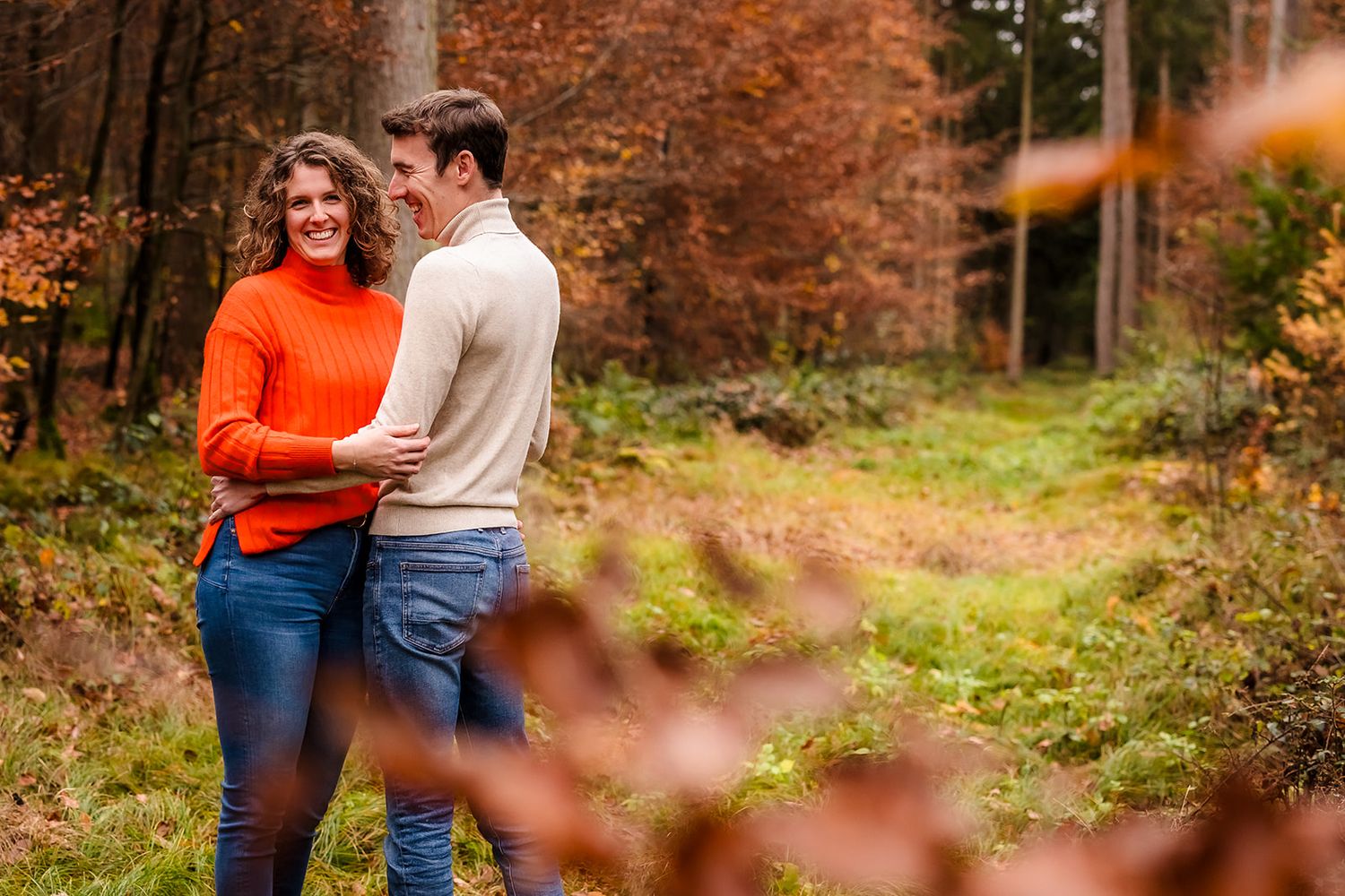 Romantic autumn engagement photoshoot in a forest with warm orange tones.
