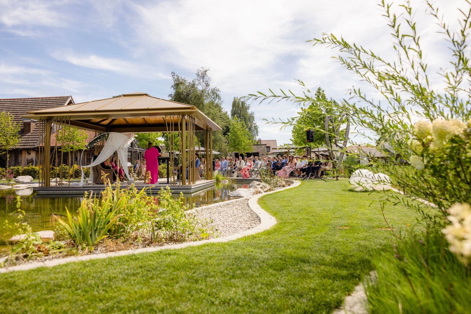 A panoramic view of a desert botanical garden pathway with native plants and landscaping under a bright blue sky.