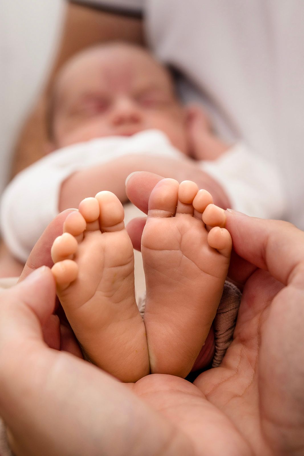 Close-up macro photo of tiny newborn baby feet against a soft white background.
