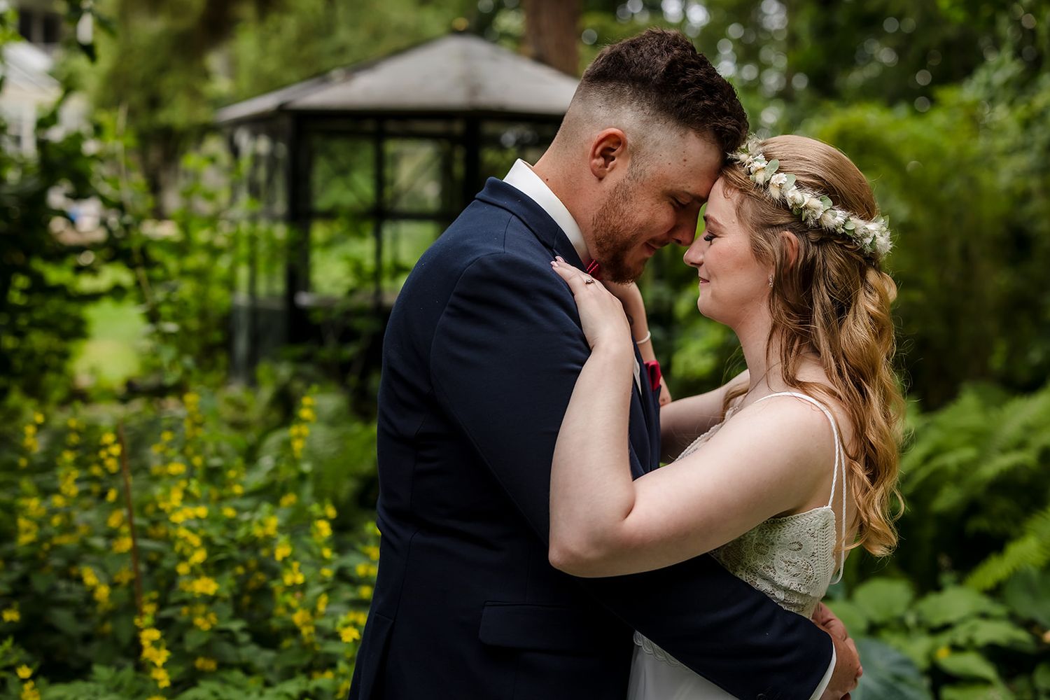 A romantic couple shares an intimate moment in a lush garden setting during their wedding celebration.