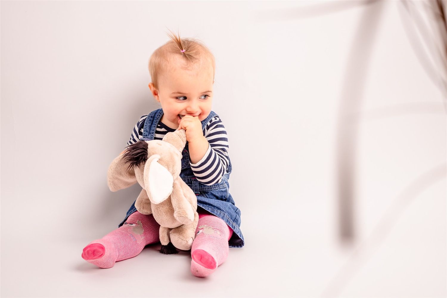 Baby in striped shirt and pink socks crawls across white background in sequential motion capture photos.