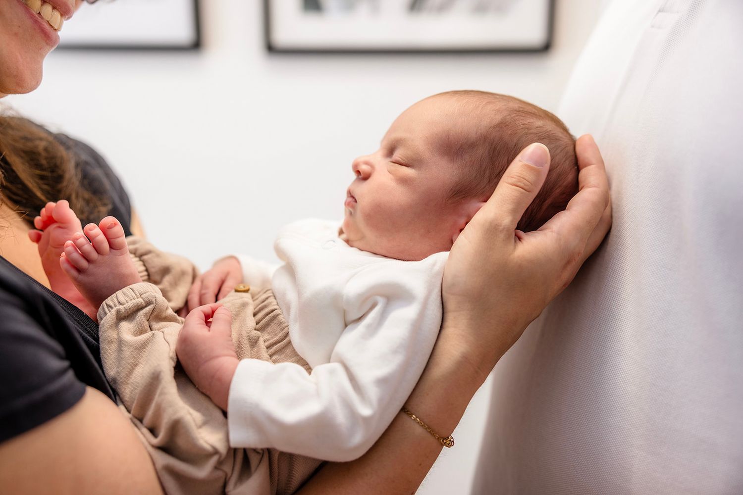 A newborn baby's hand gently grasps a parent's finger during a tender moment.