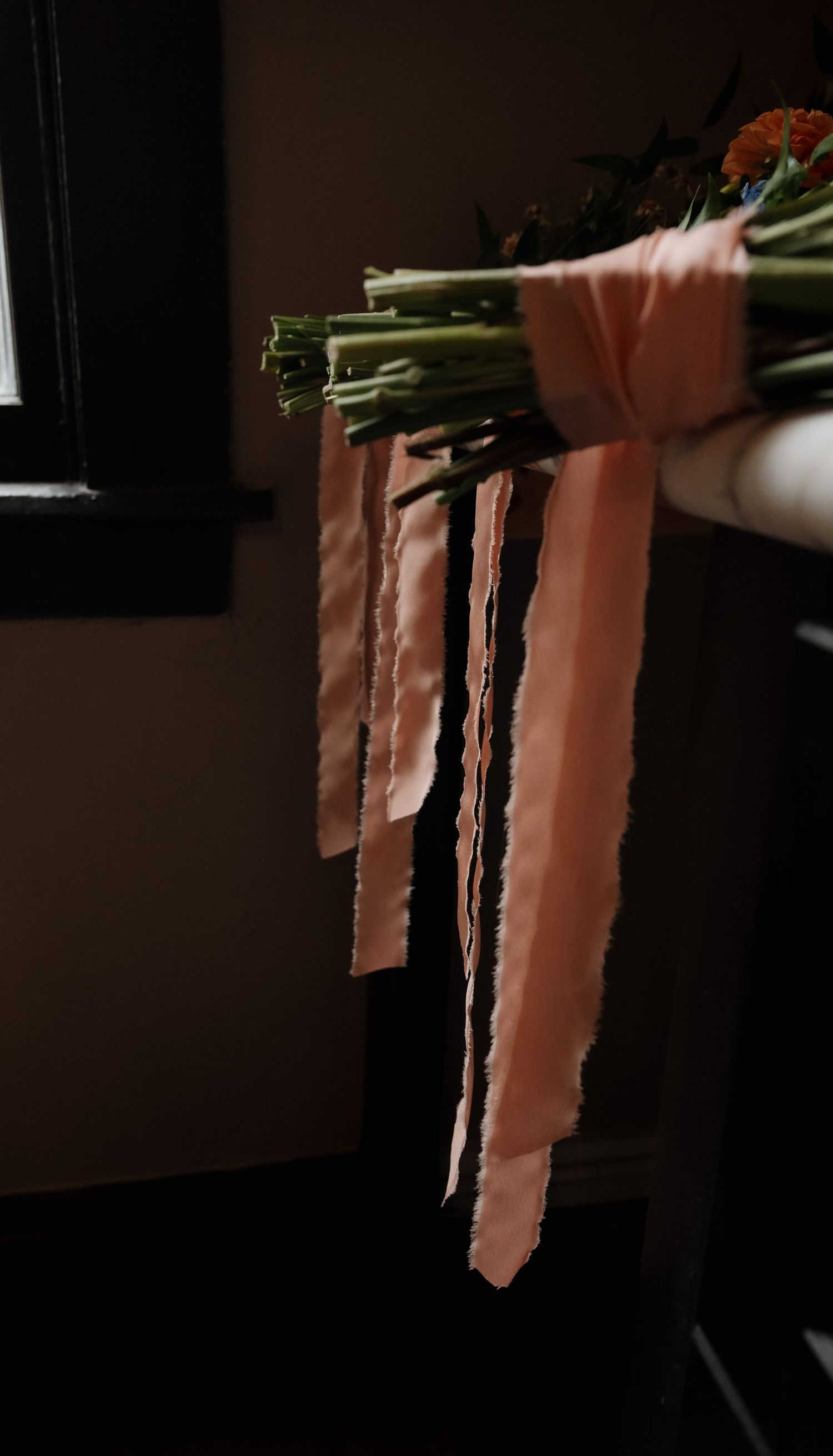 Pink fabric ribbons hanging dramatically in dark moody lighting.