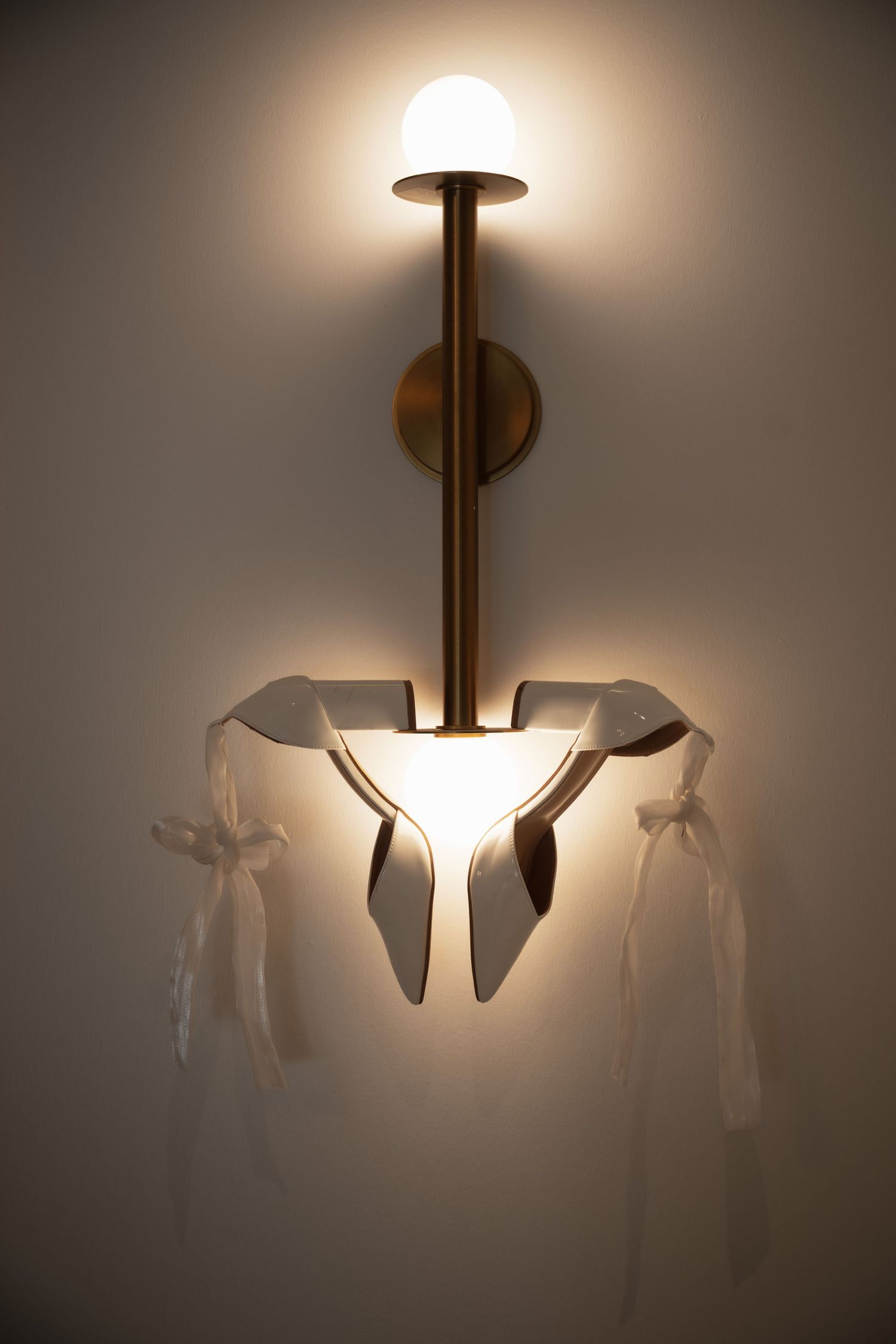 Artistic lighting fixture casting shadows on neutral wall.