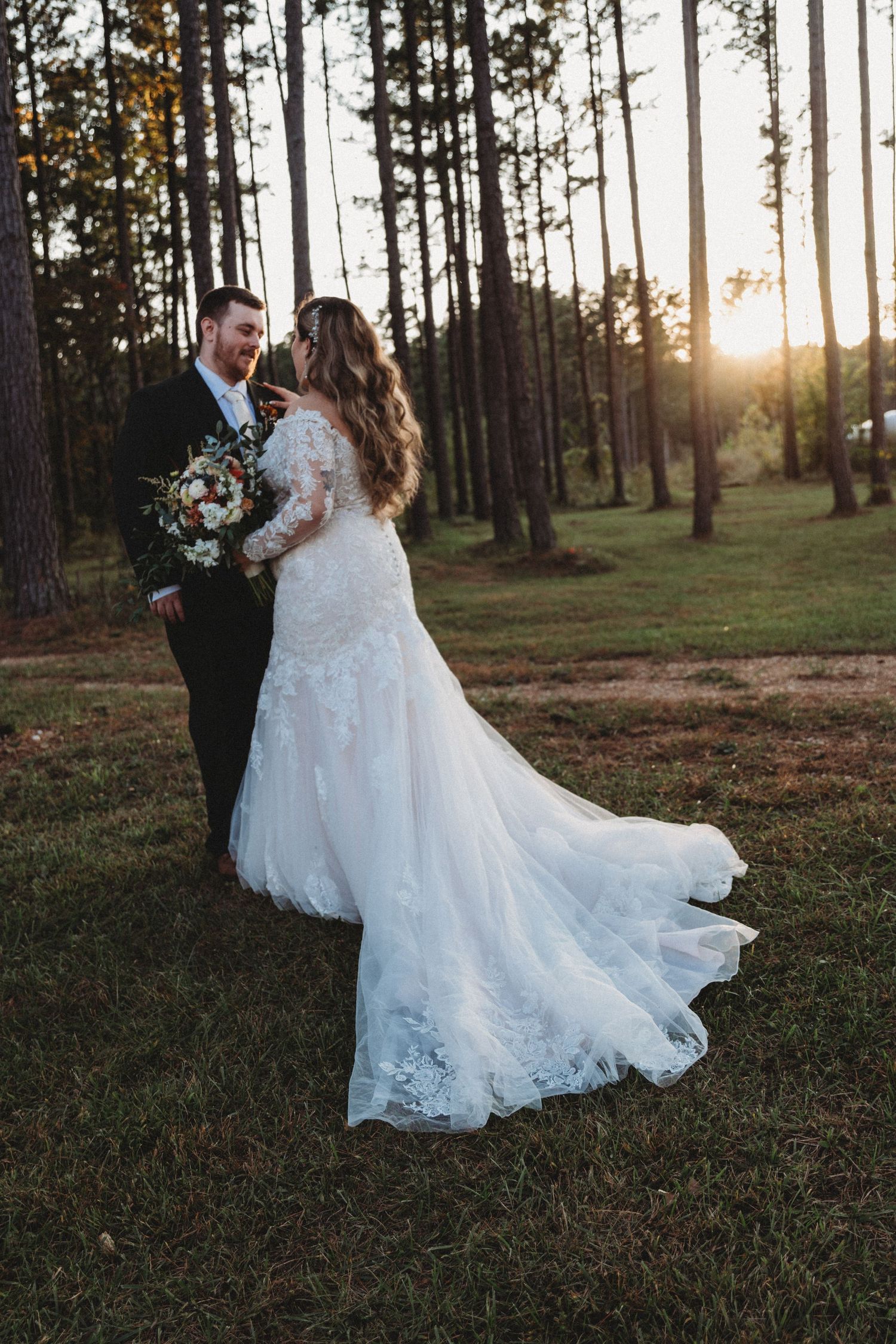 Wedding couple walking through a pine forest at sunset with flowing white dress.