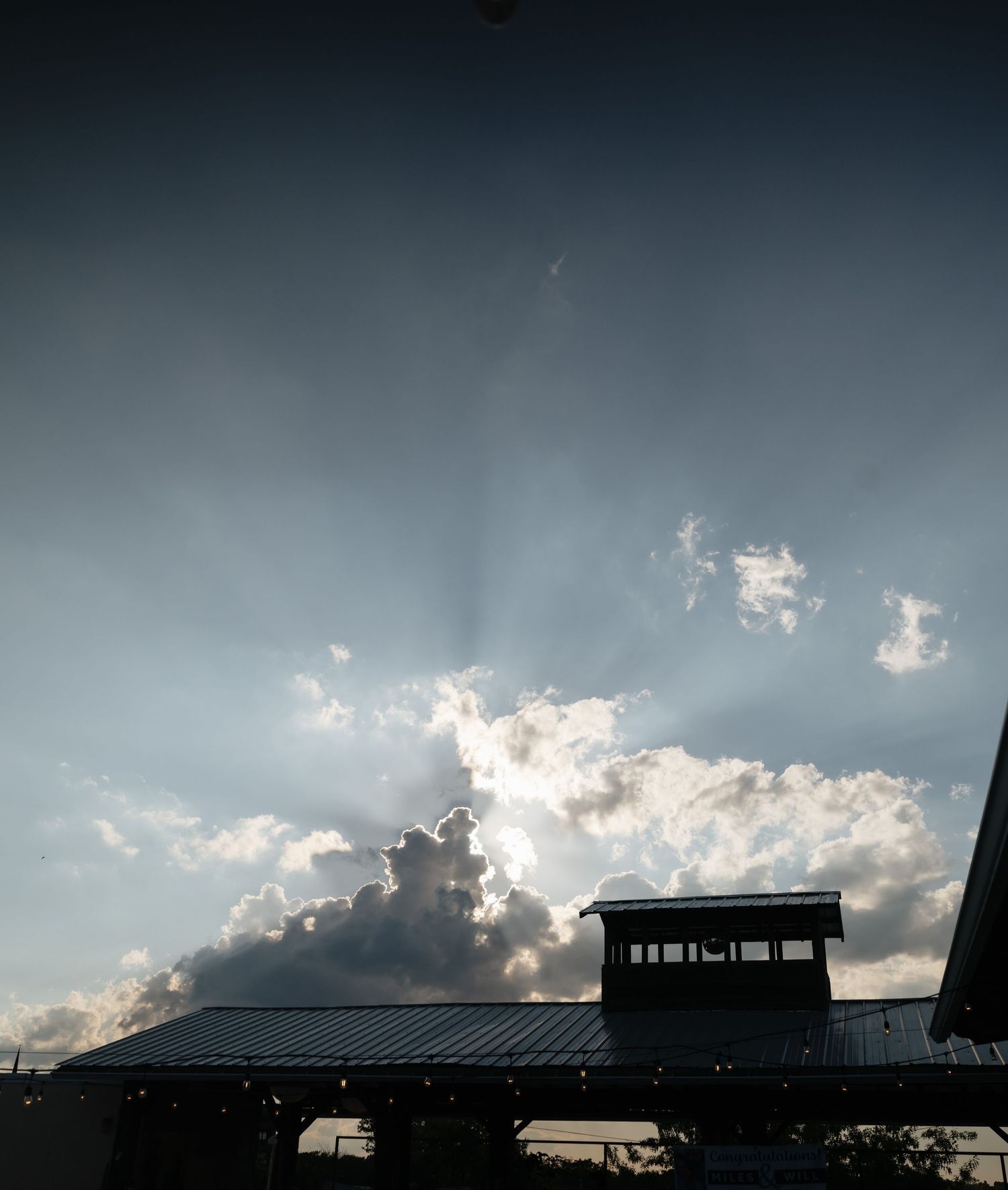 A dramatic panoramic skyline silhouette against stormy clouds during sunset with buildings visible in dark shadow.