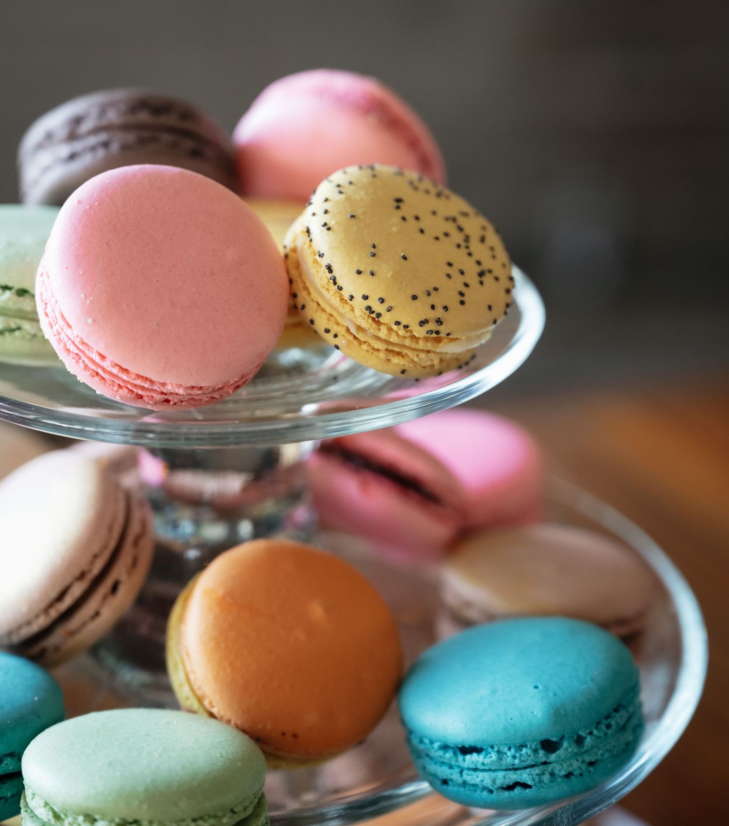 Colorful French macarons in pastel pink, yellow, blue and brown arranged on glass plates.