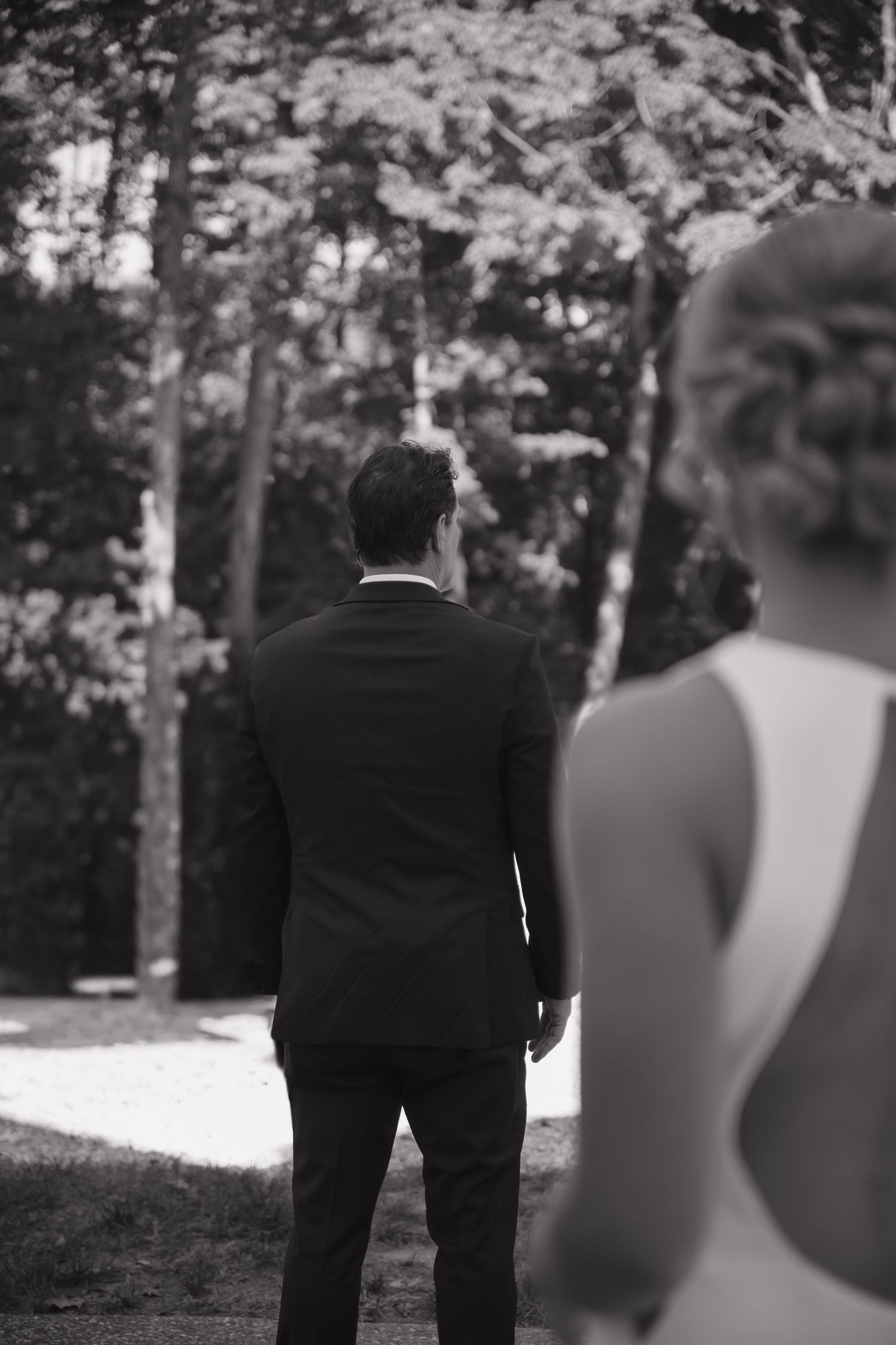 A black and white photo series showing people walking in a wooded area with trees in the background.