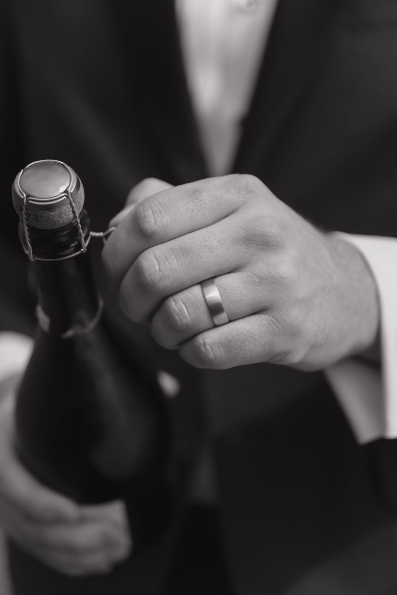 Black and white detail of hands holding wedding rings.