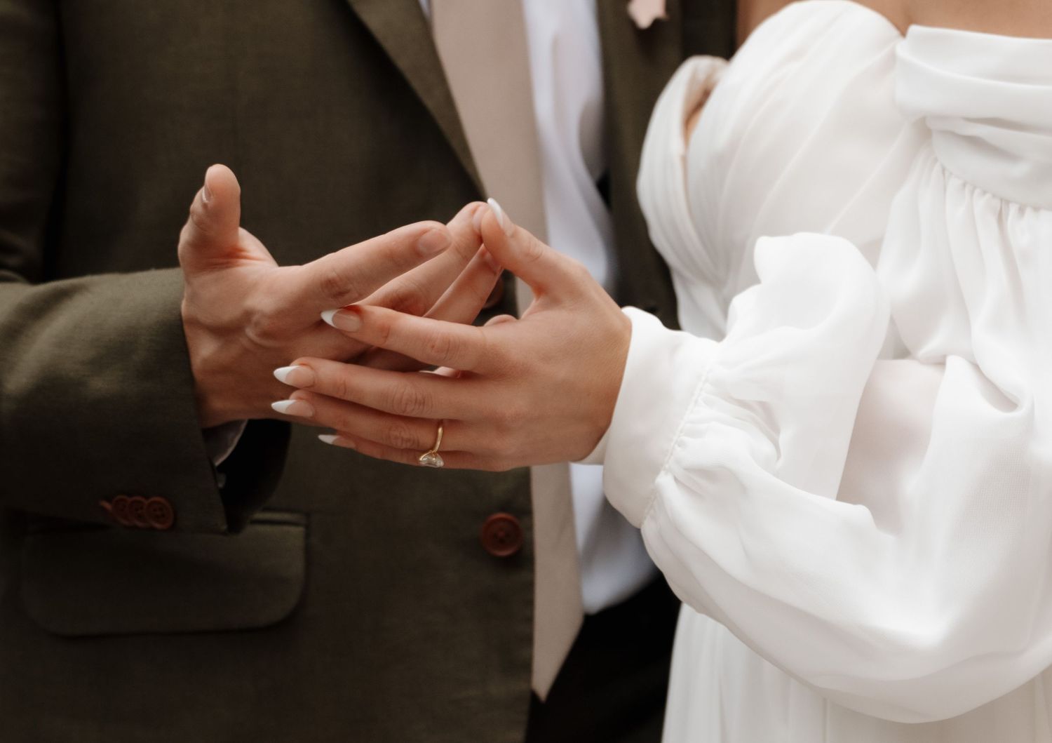 Close-up shot of hands exchanging wedding rings during a marriage ceremony.