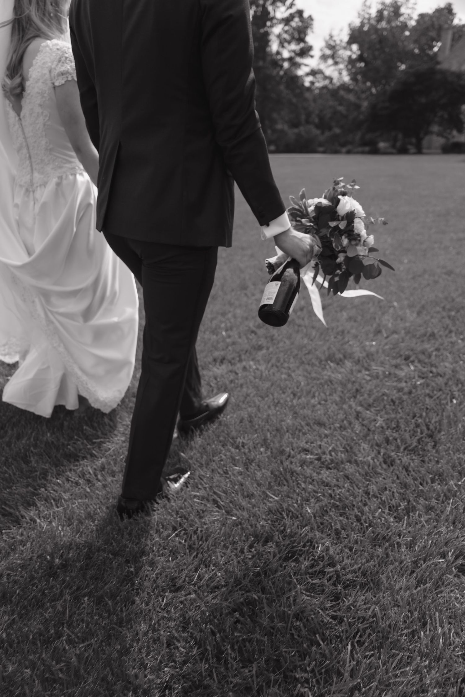 Black and white wedding photo showing couple's feet walking on grass.