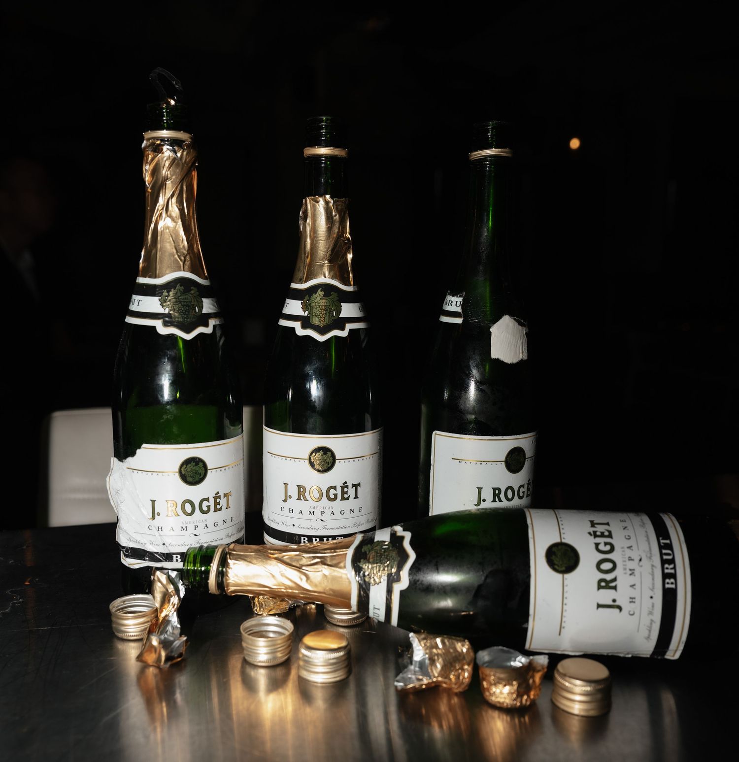 Dark artistic photo of wine bottles lined up in low light.