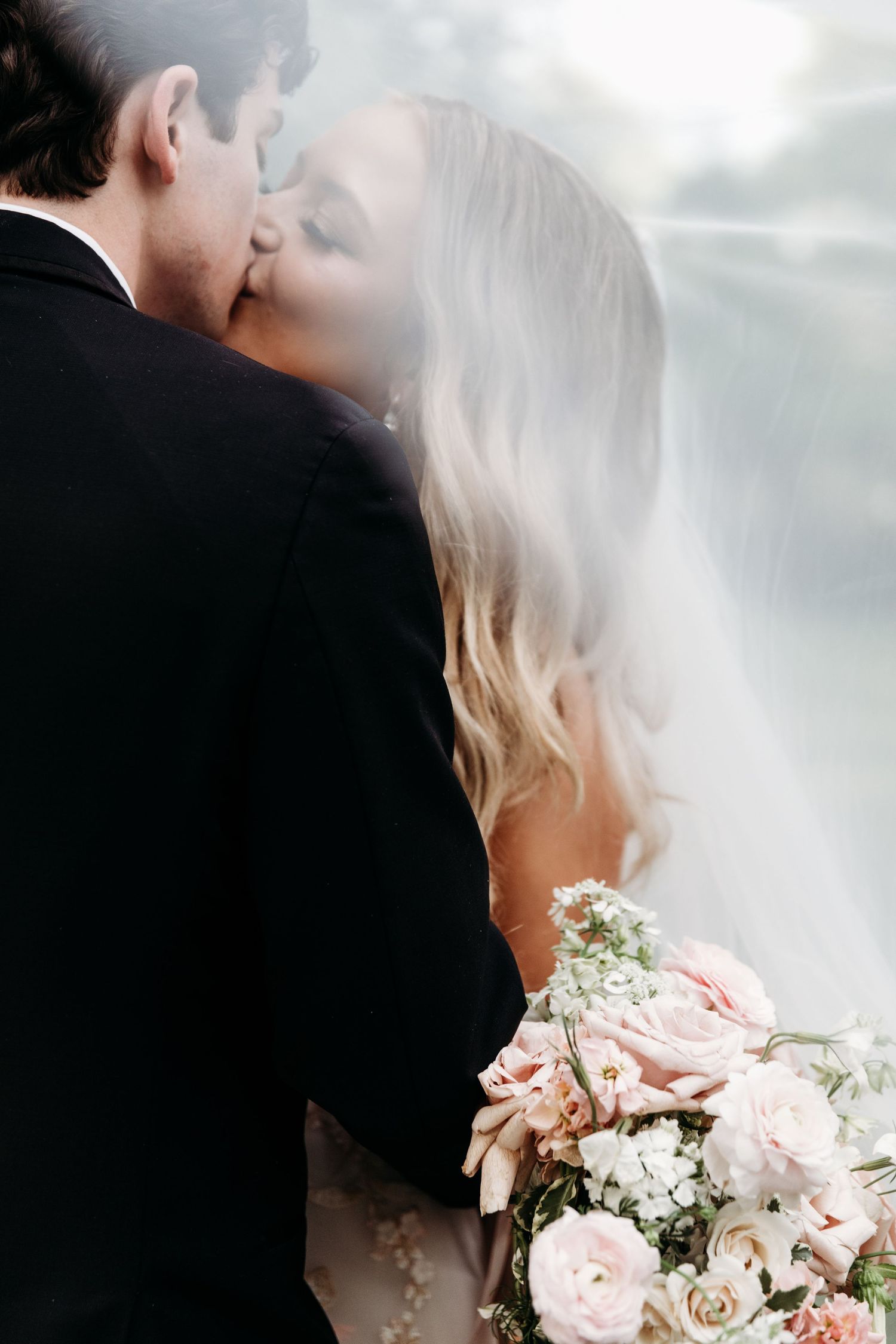 Romantic moment with soft pink roses and white flowers in the foreground.