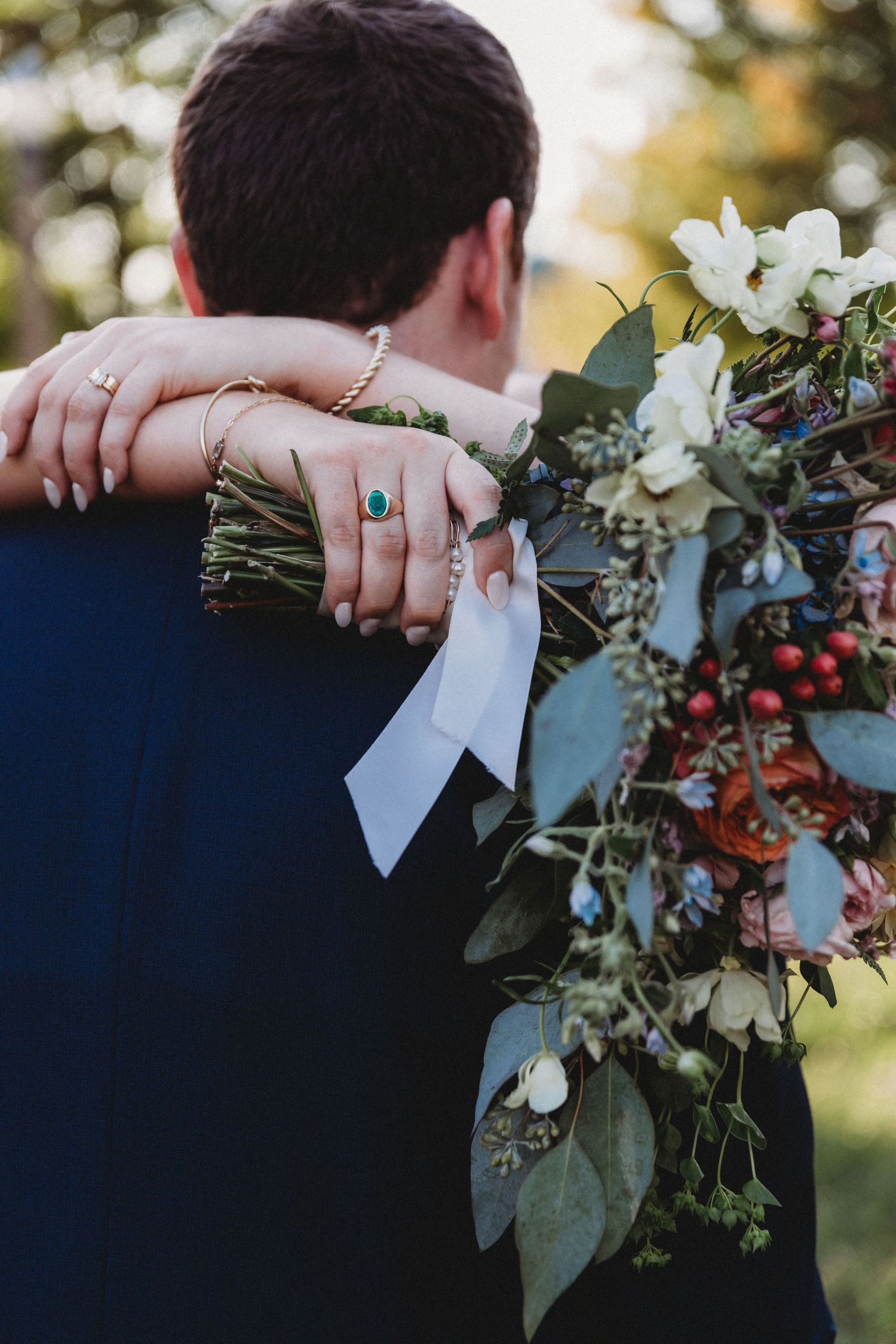 Close-up of hands holding a wedding bouquet with white flowers and greenery.