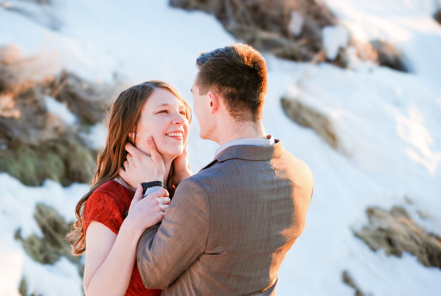 A romantic winter photoshoot featuring a couple embracing against a snowy backdrop.