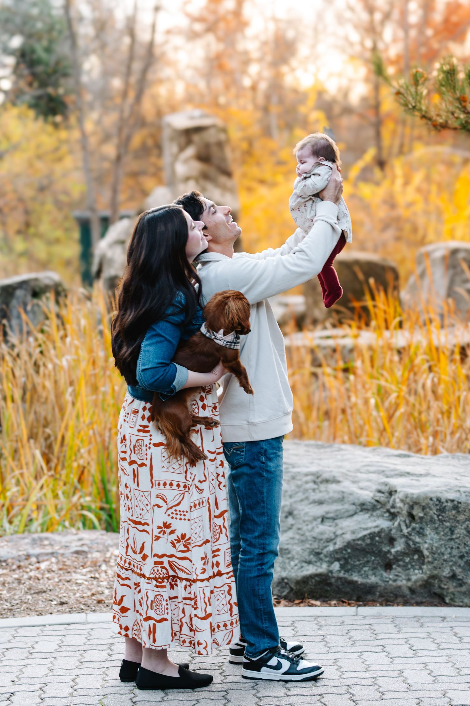 Parent and child playing together outdoors in autumn with fallen leaves.