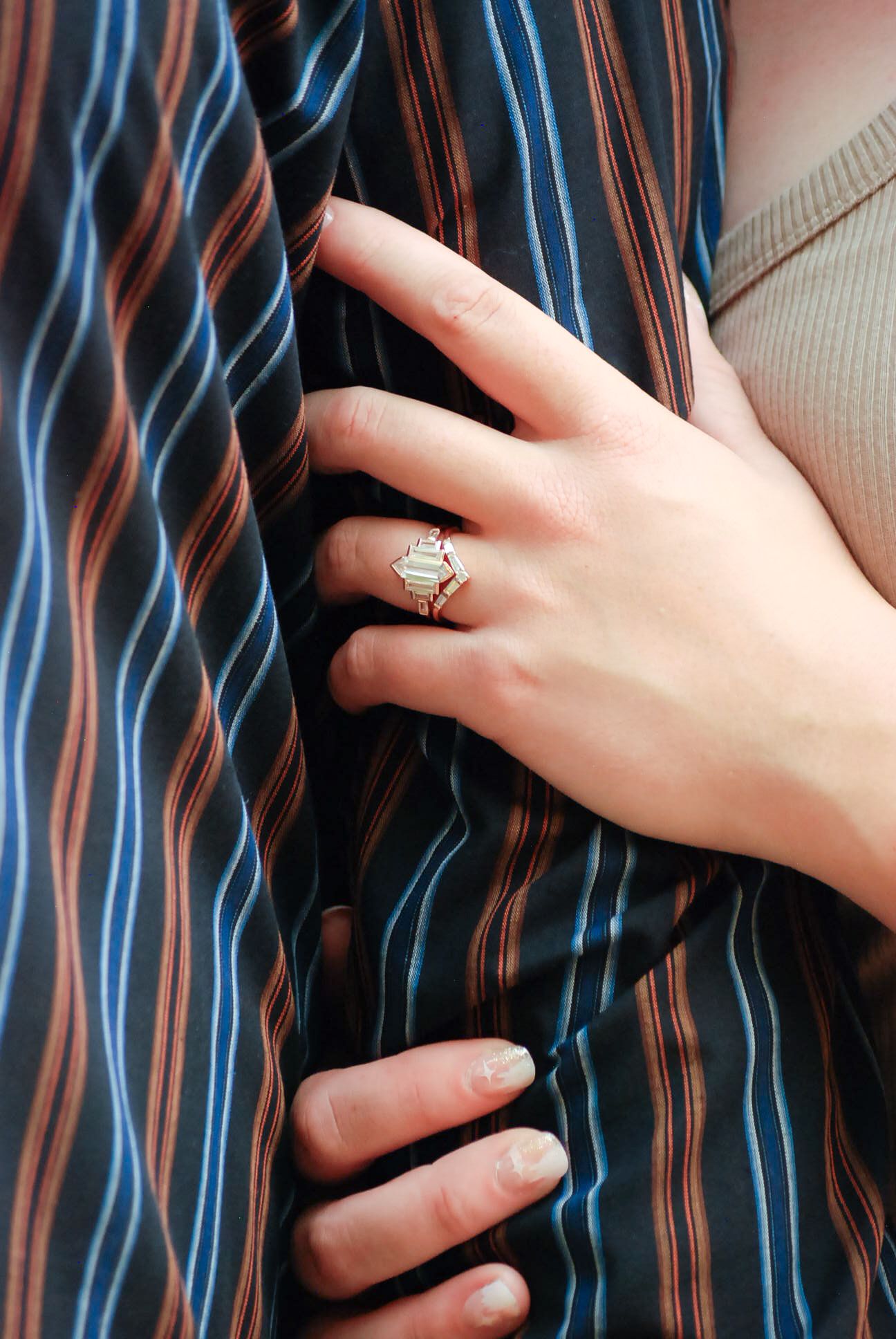Close-up shots of hands against a striped shirt showing engagement ring details.