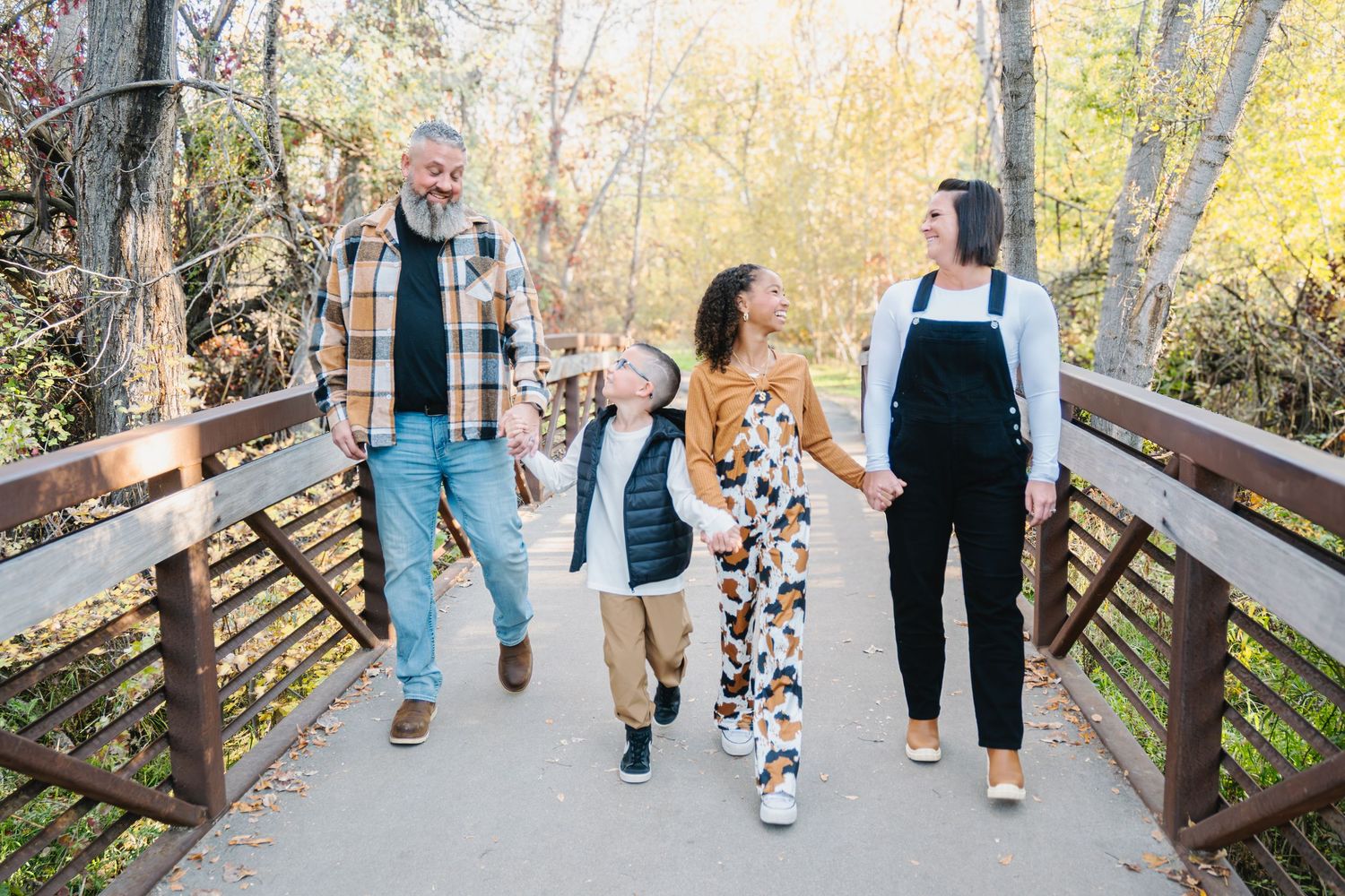 Family members walking together on a wooden bridge path during autumn.