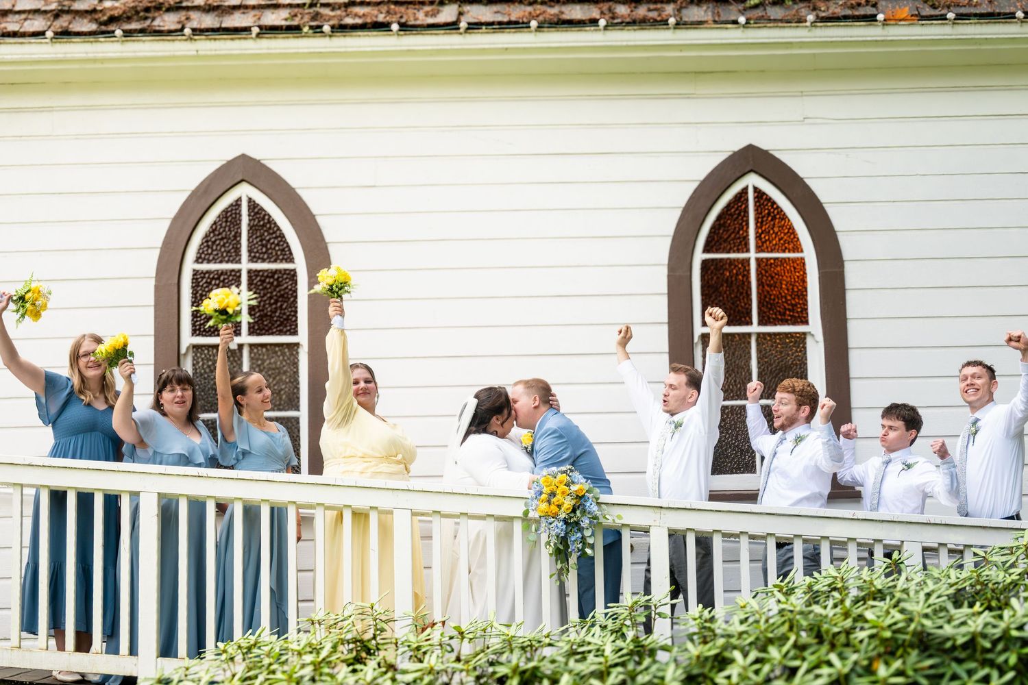 Wedding guests gather on a white porch of a traditional venue during a celebration.