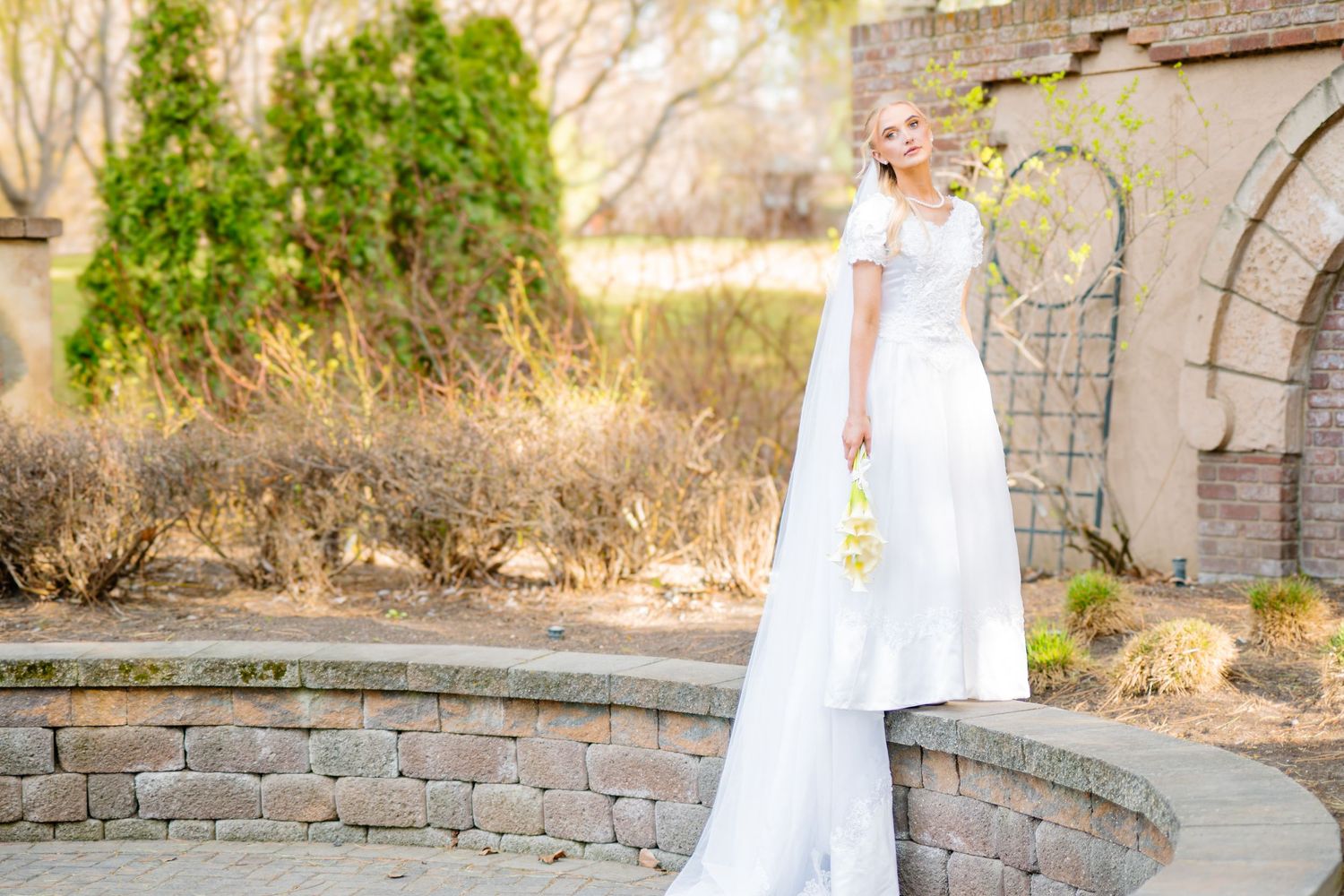A series of wedding photos showing a bride in a white dress walking along a stone wall path in a garden setting.