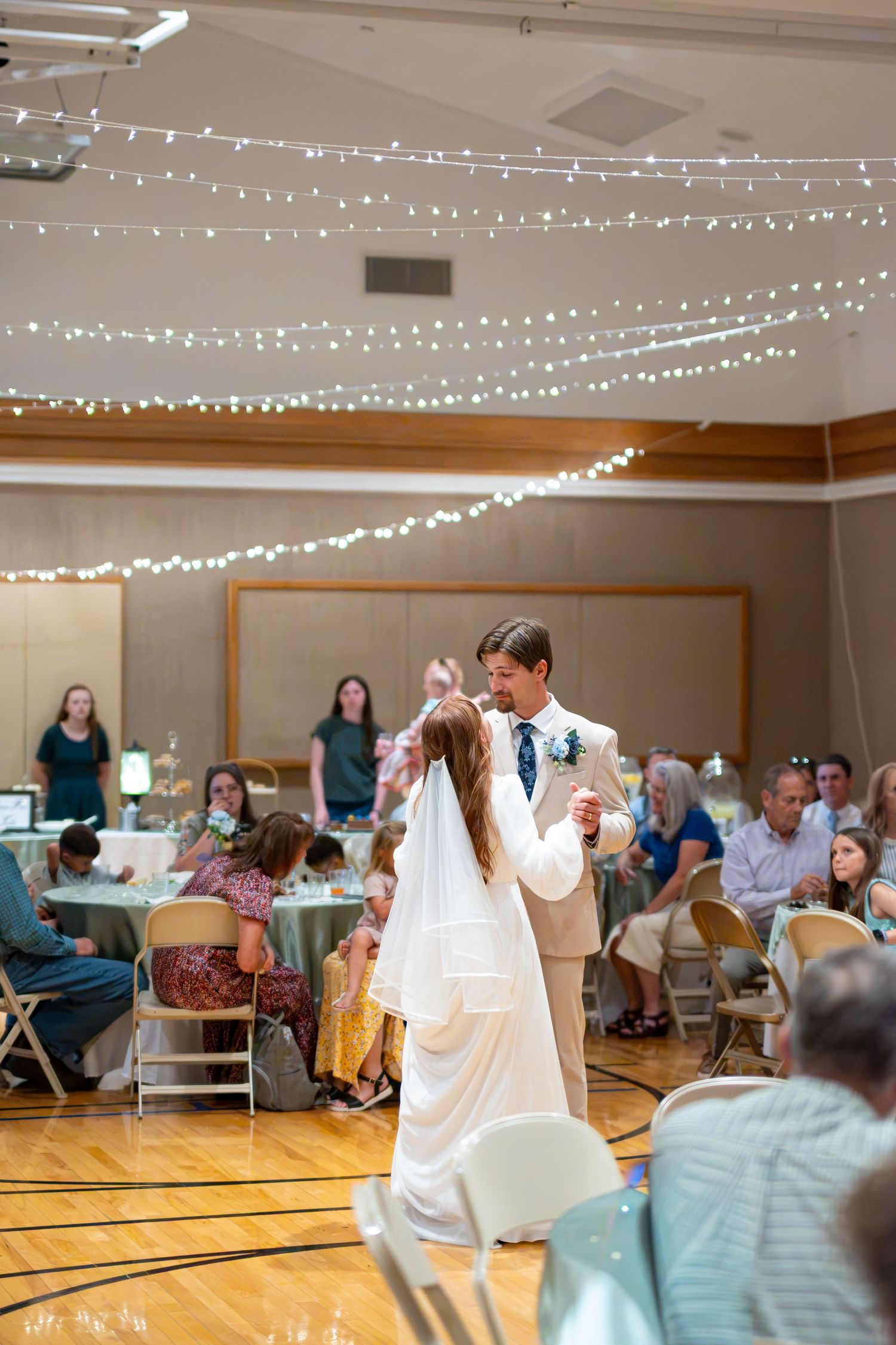 Bride and groom share their first dance under twinkling fairy lights at their wedding reception.