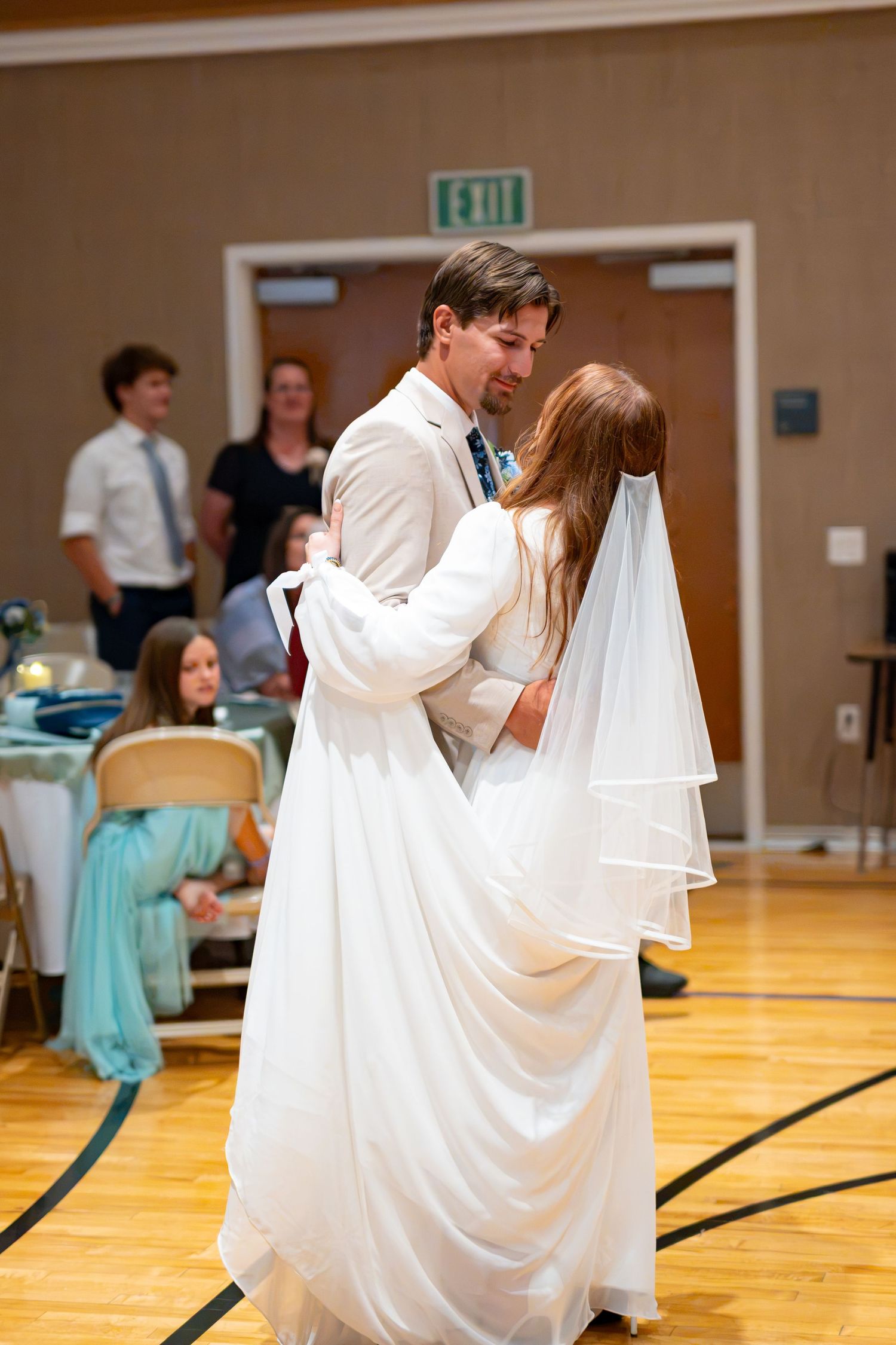 Bride and groom share their first dance in a wedding reception hall, bride in white gown with veil.