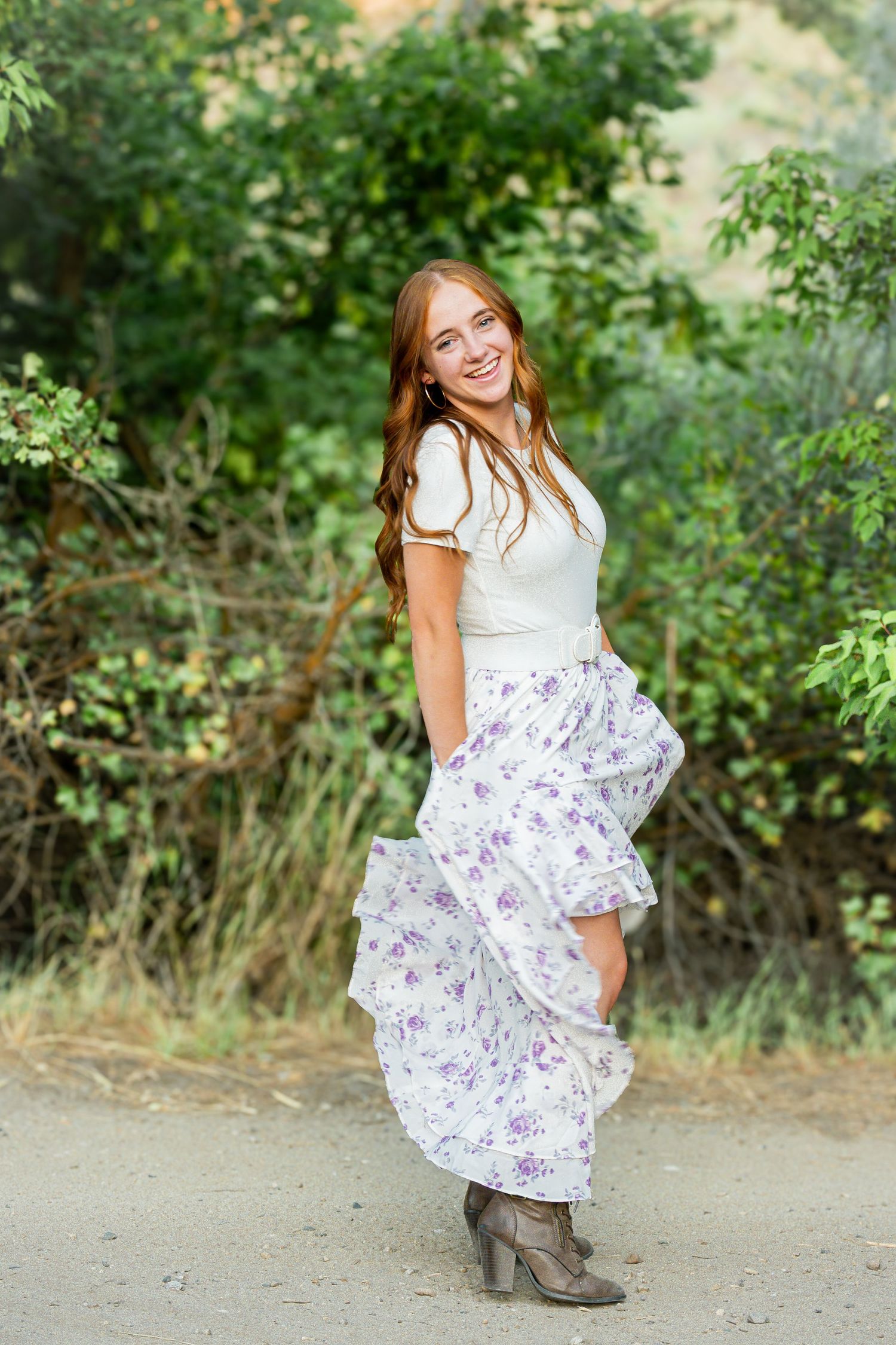 Woman in floral dress posing outdoors in natural lighting.