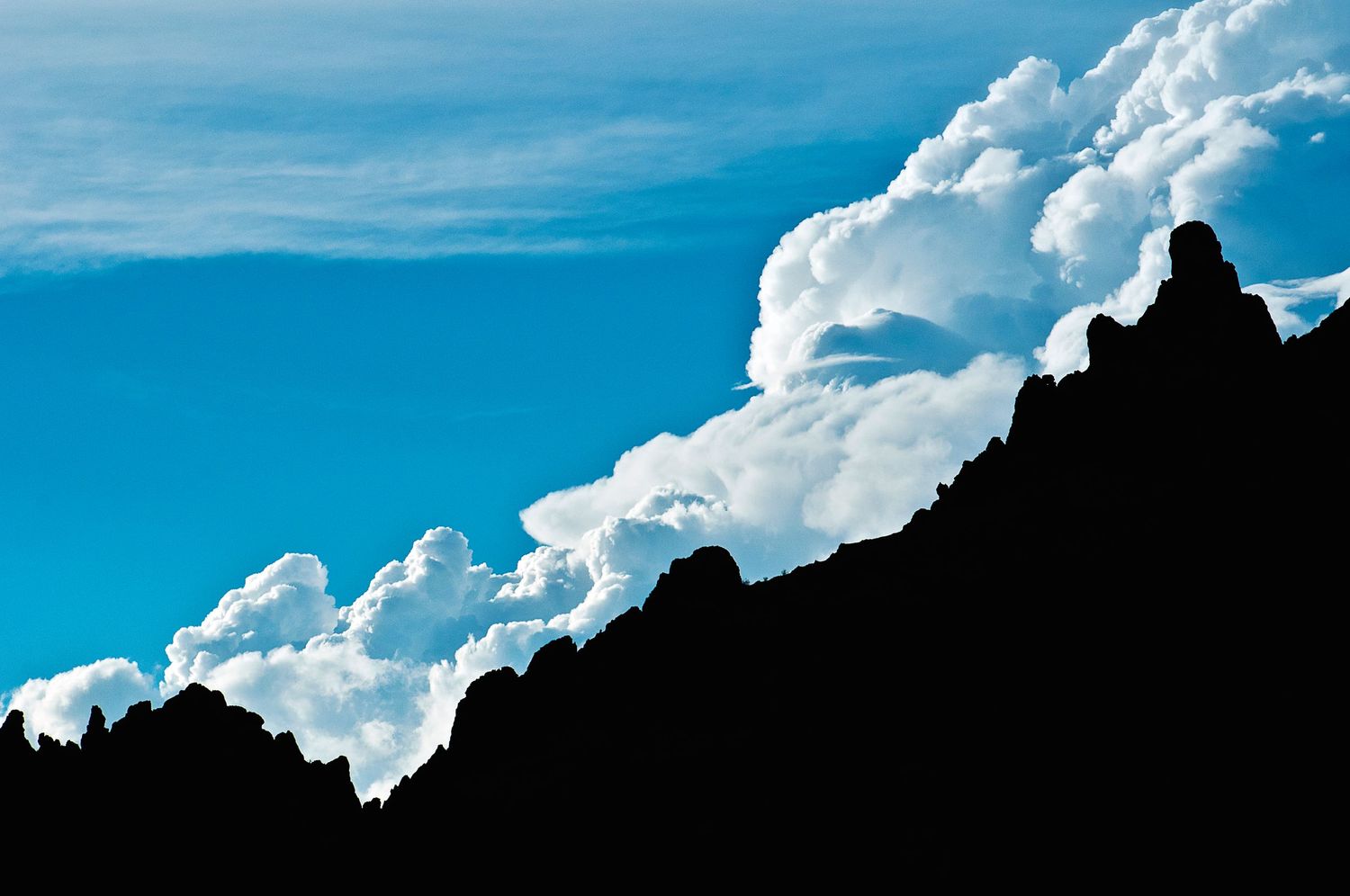 Dramatic white clouds against bright blue sky forming a panoramic skyscape.