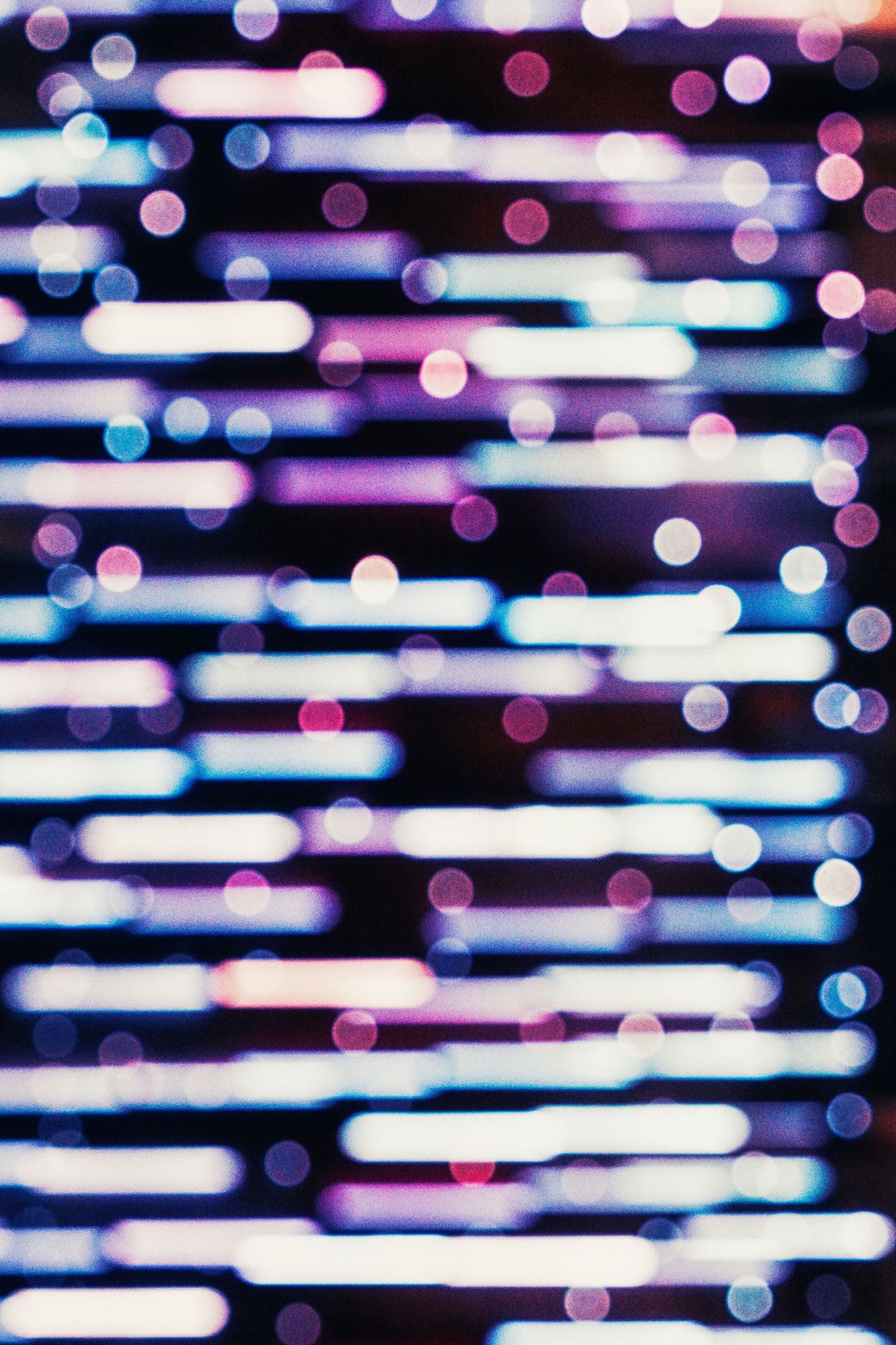 Abstract blurred bokeh background with horizontal light streaks in purple, blue and white colors.
