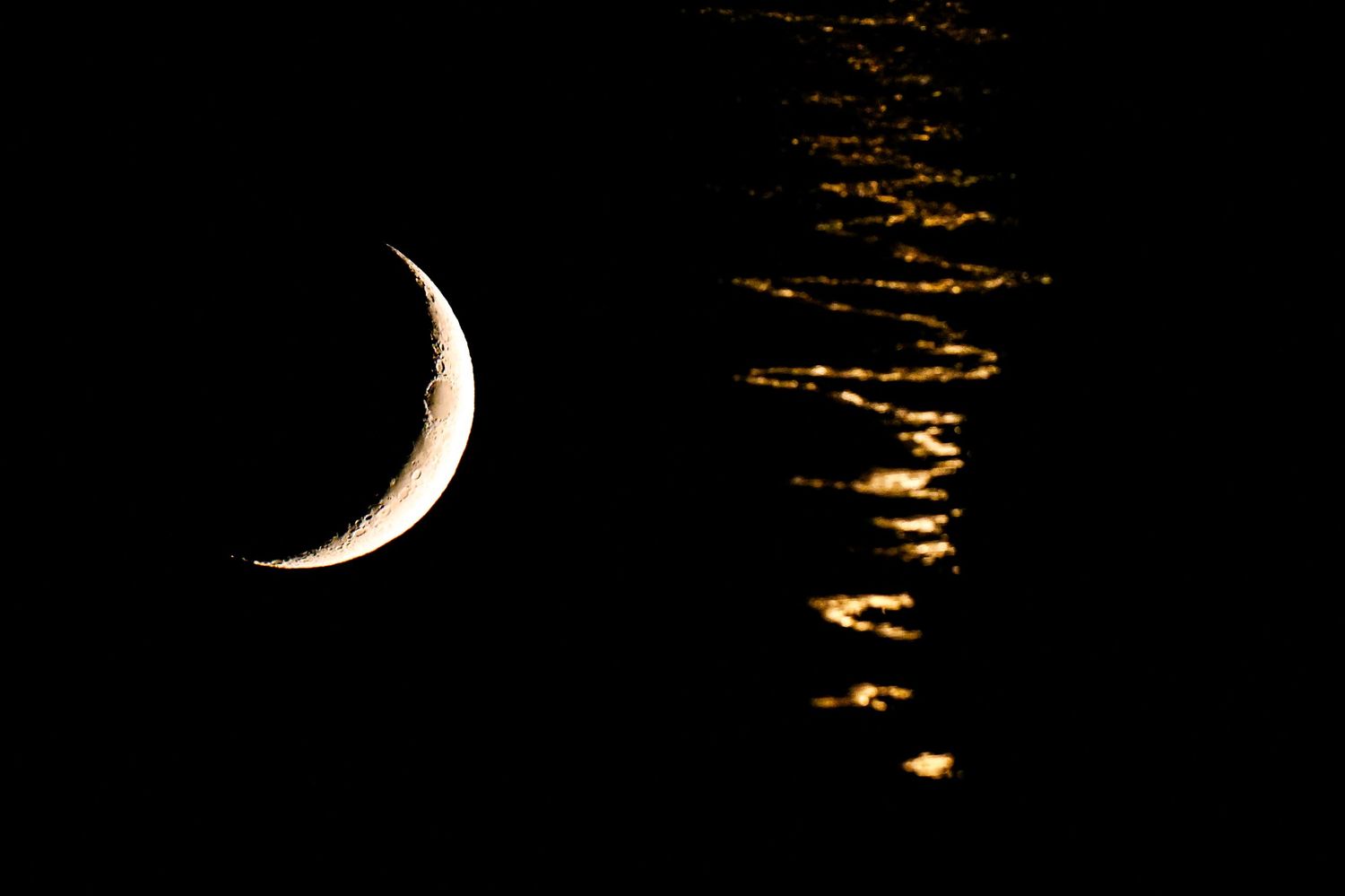 Crescent moon glowing against a dark night sky with golden illuminated clouds on the right side.
