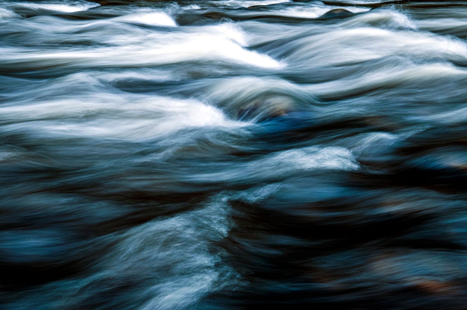 Abstract long exposure of flowing water creating smooth blue and white patterns.