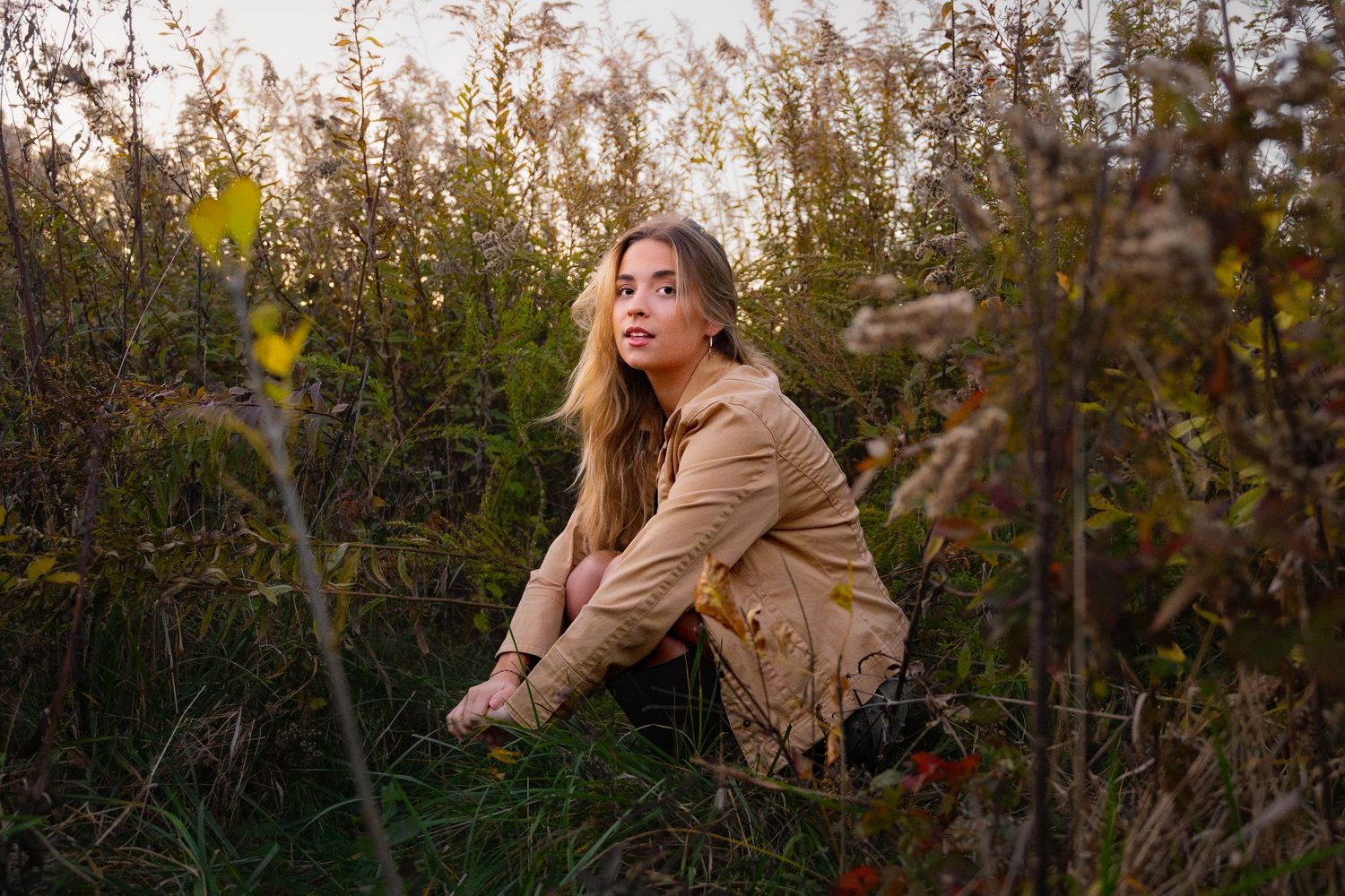 Autumn outdoor portraits in golden light among dried plants and branches.