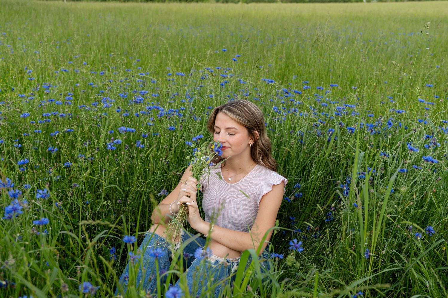 People relaxing in a sunny meadow filled with blue wildflowers.