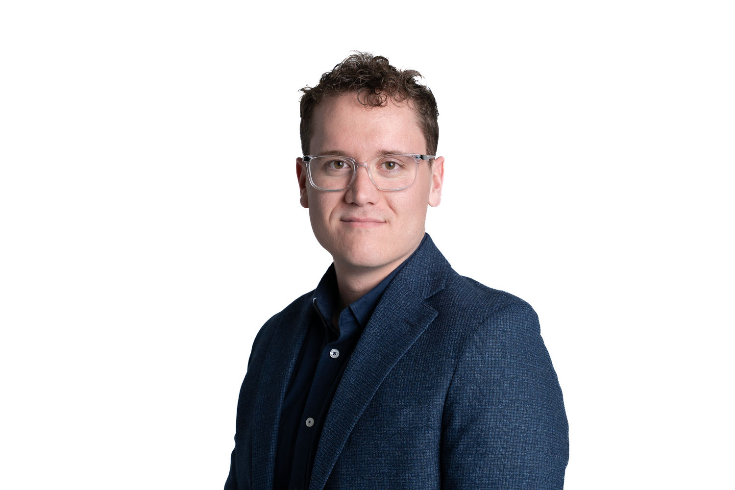 Professional headshot of someone wearing glasses and a navy blue blazer against a white background.